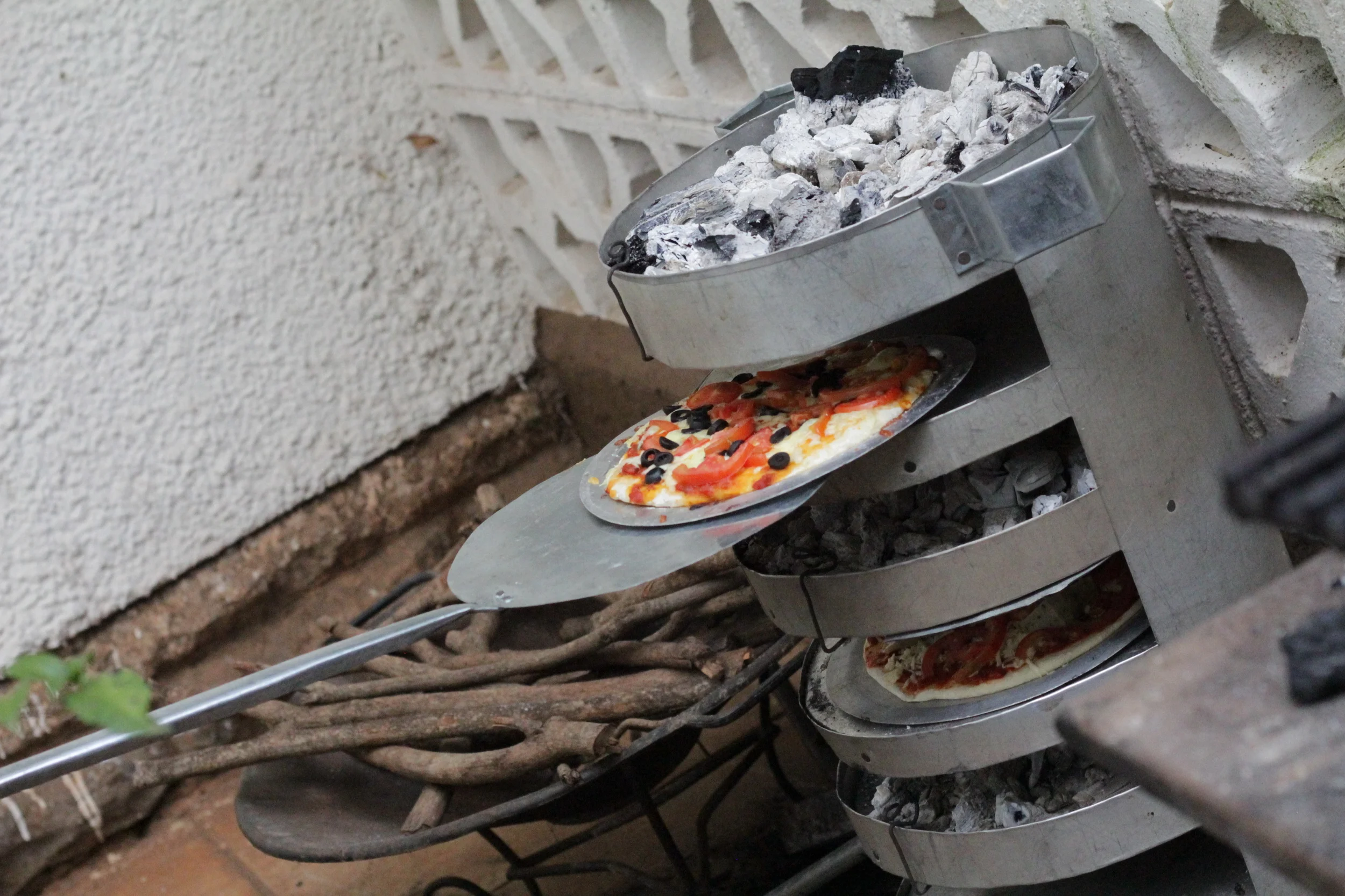 Charcoal beneath and above the pizza grills cooks the pizzas to crisp perfection