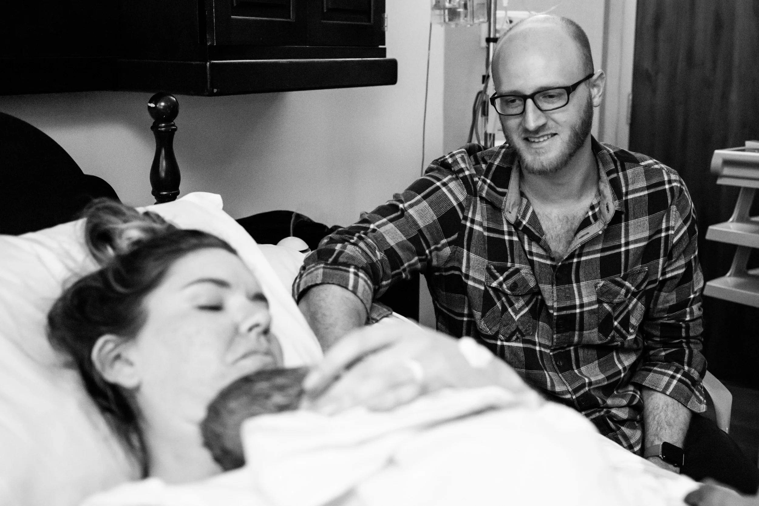 husband looks lovingly at wife and newborn baby