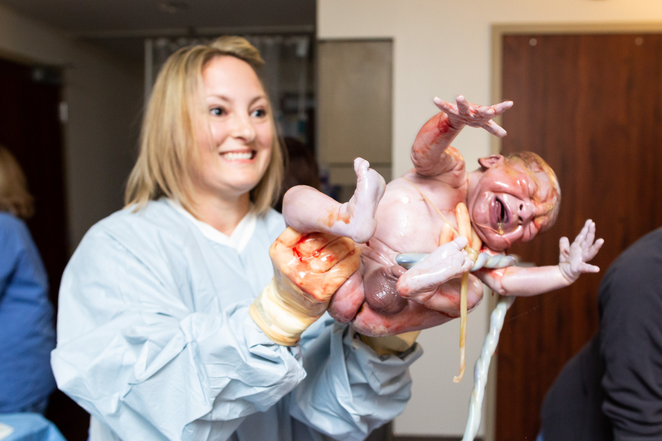 midwife holds up baby after birth