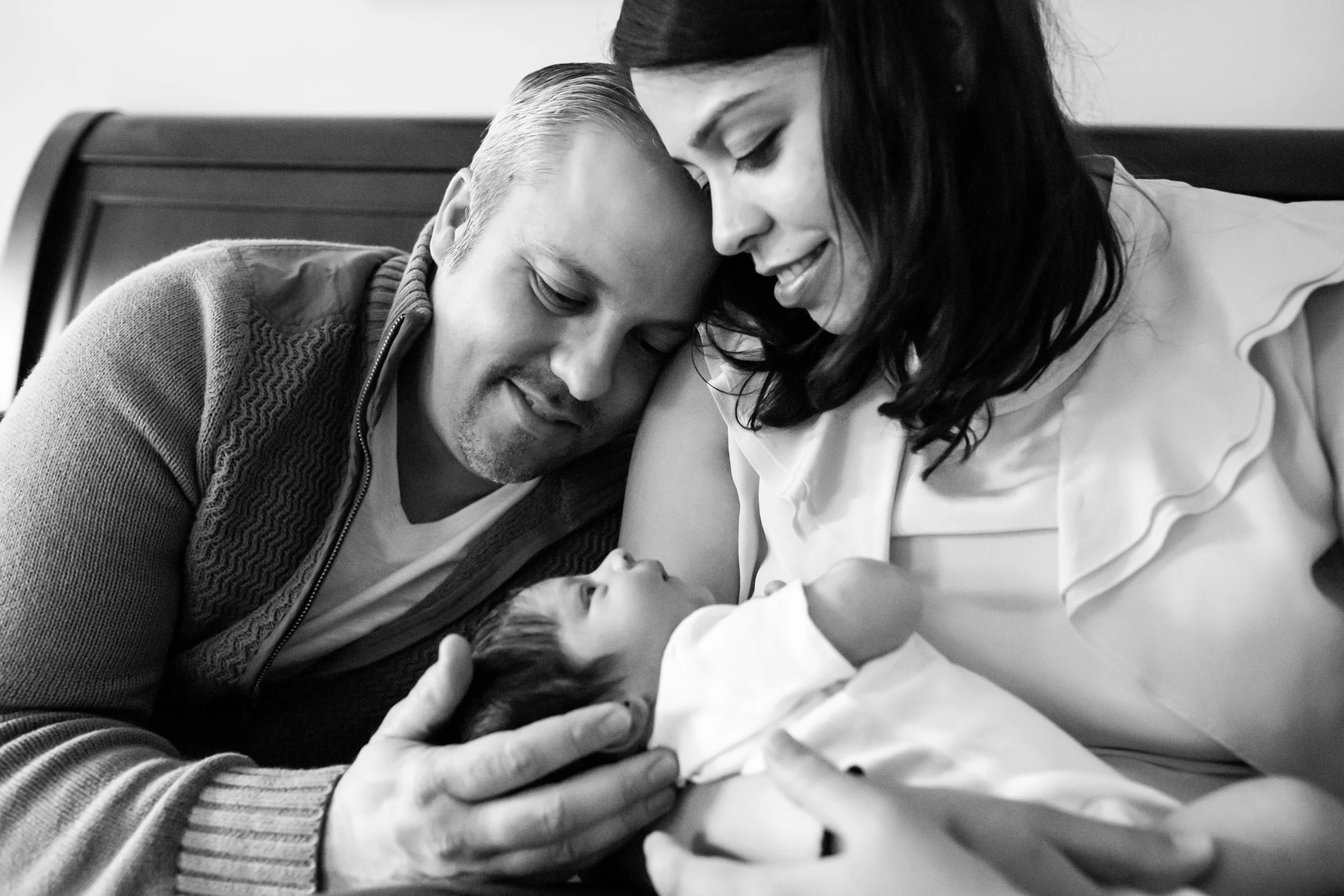 dad and mom cuddling with newborn
