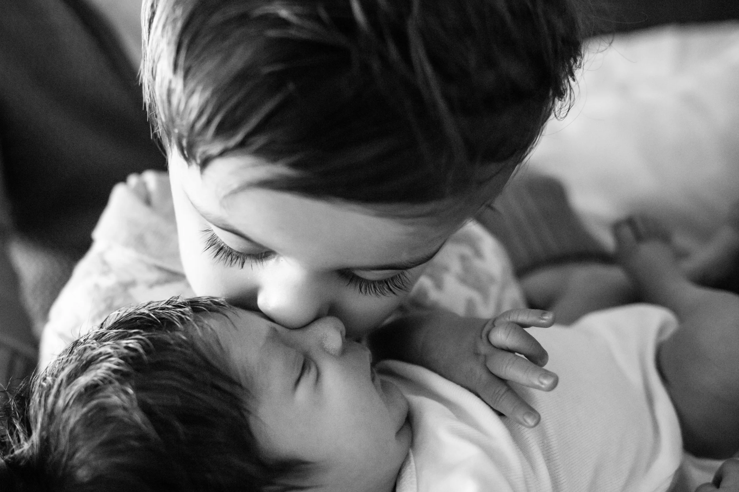 older brother kissing newborn baby boy