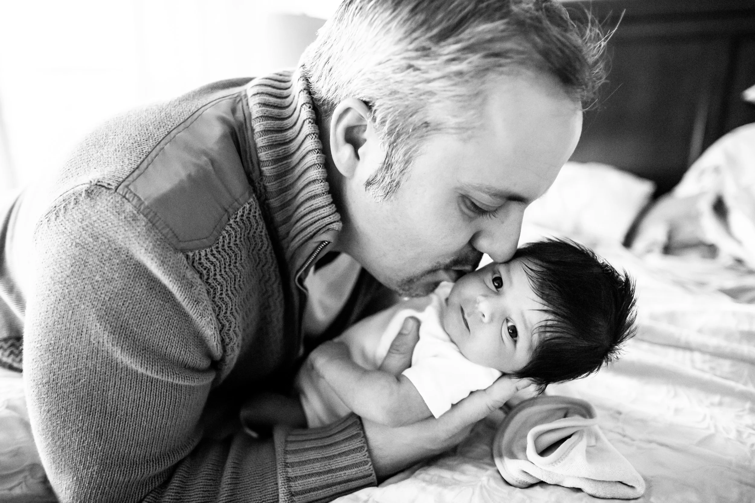 father kissing newborn