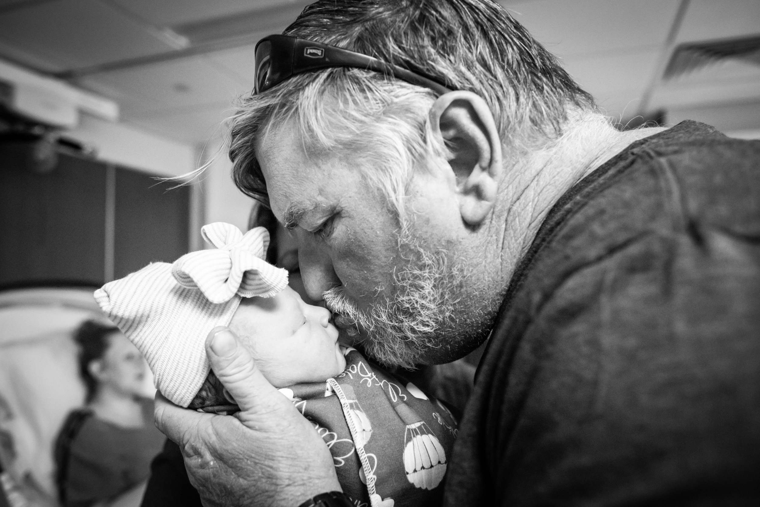 grandfather kissing his newborn granddaughter