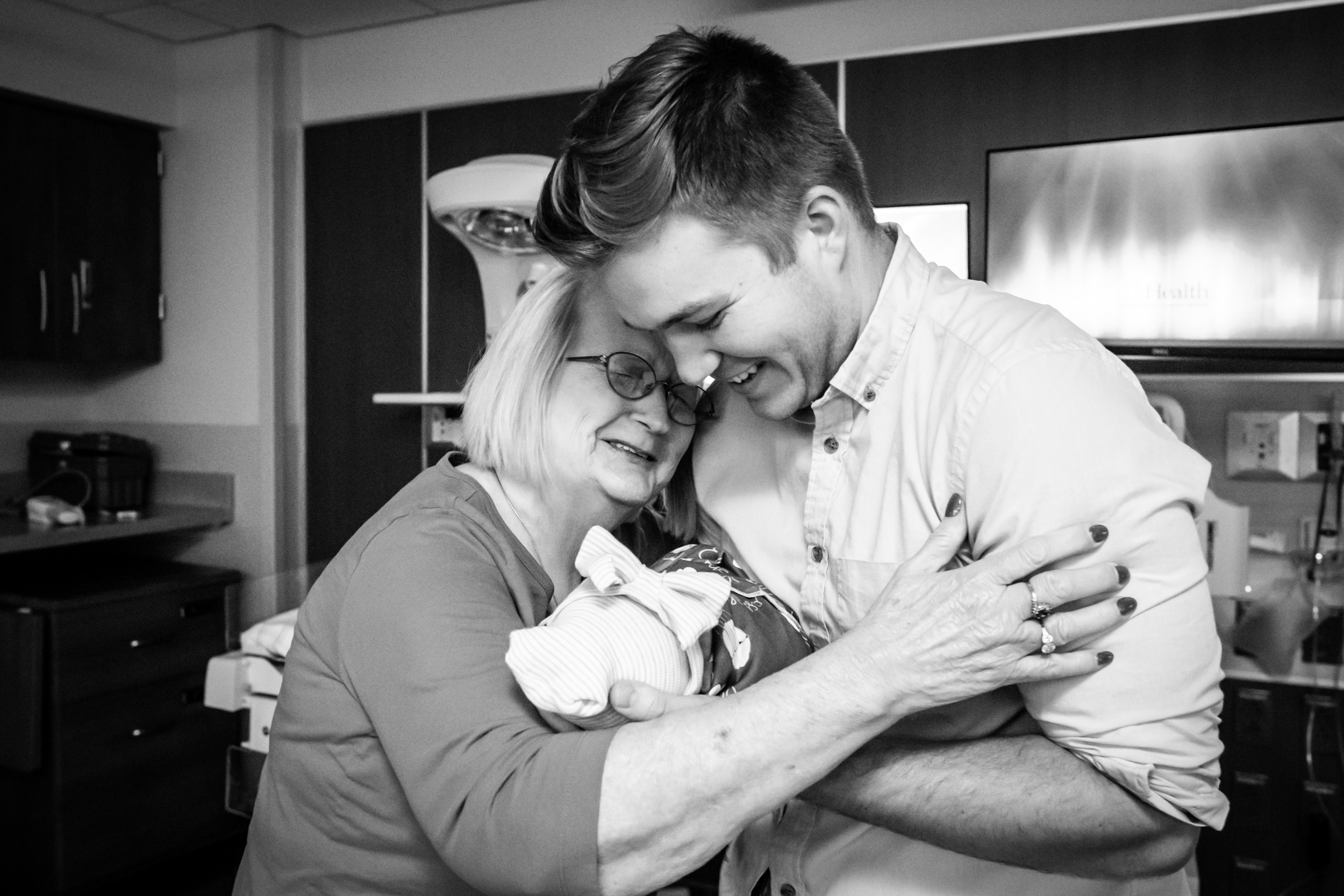 great-grandmother hugging grandson and newborn baby