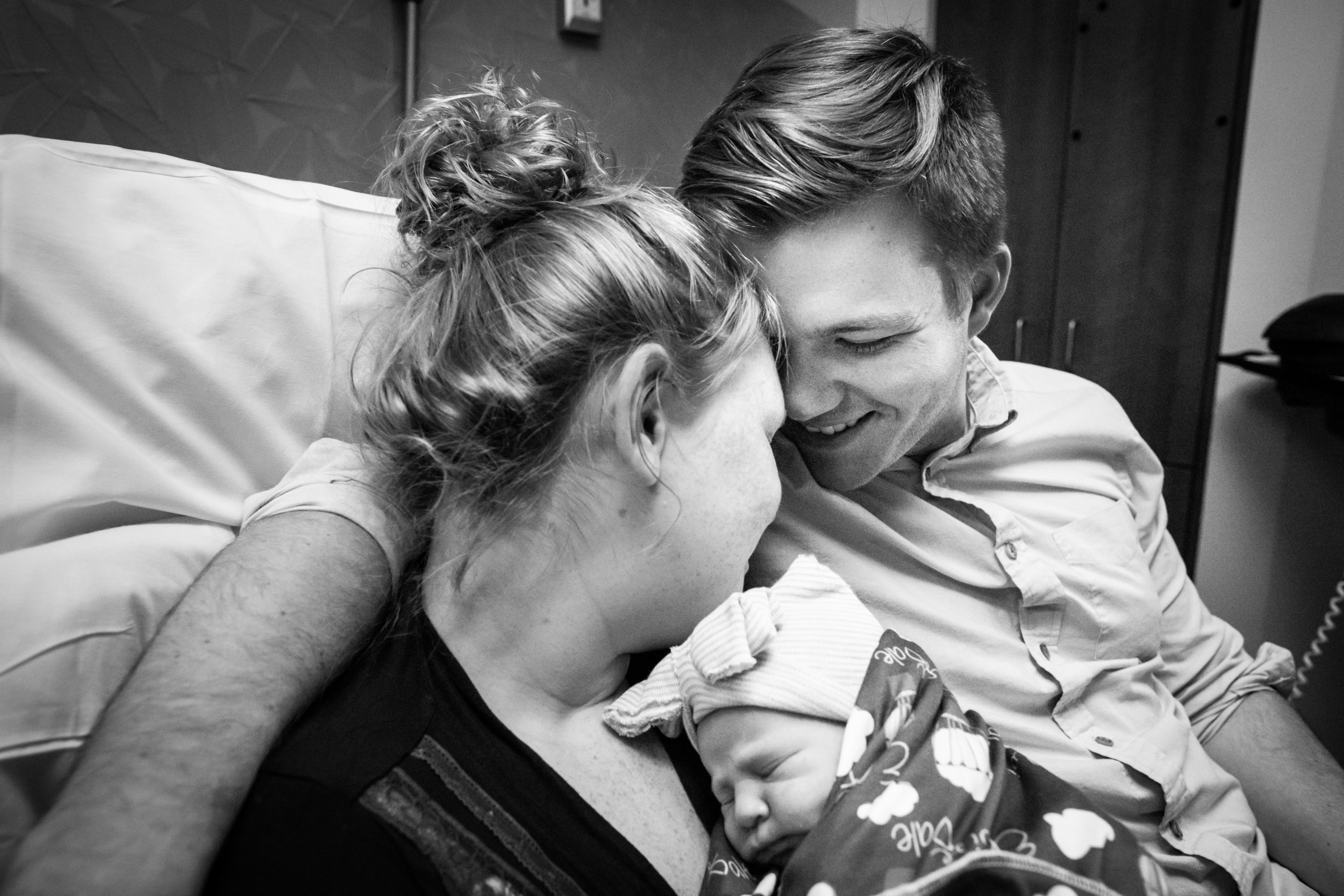 new parents with heads together and smiling