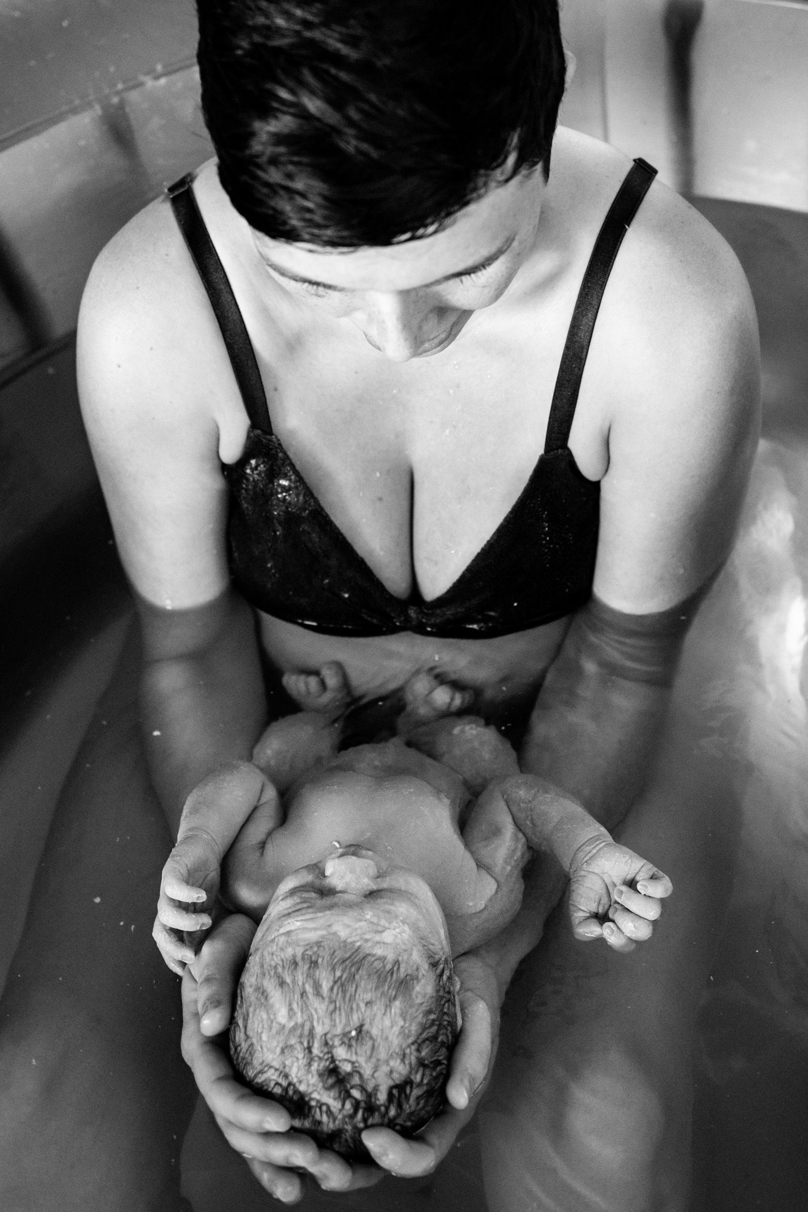 mom holding newborn baby in tub