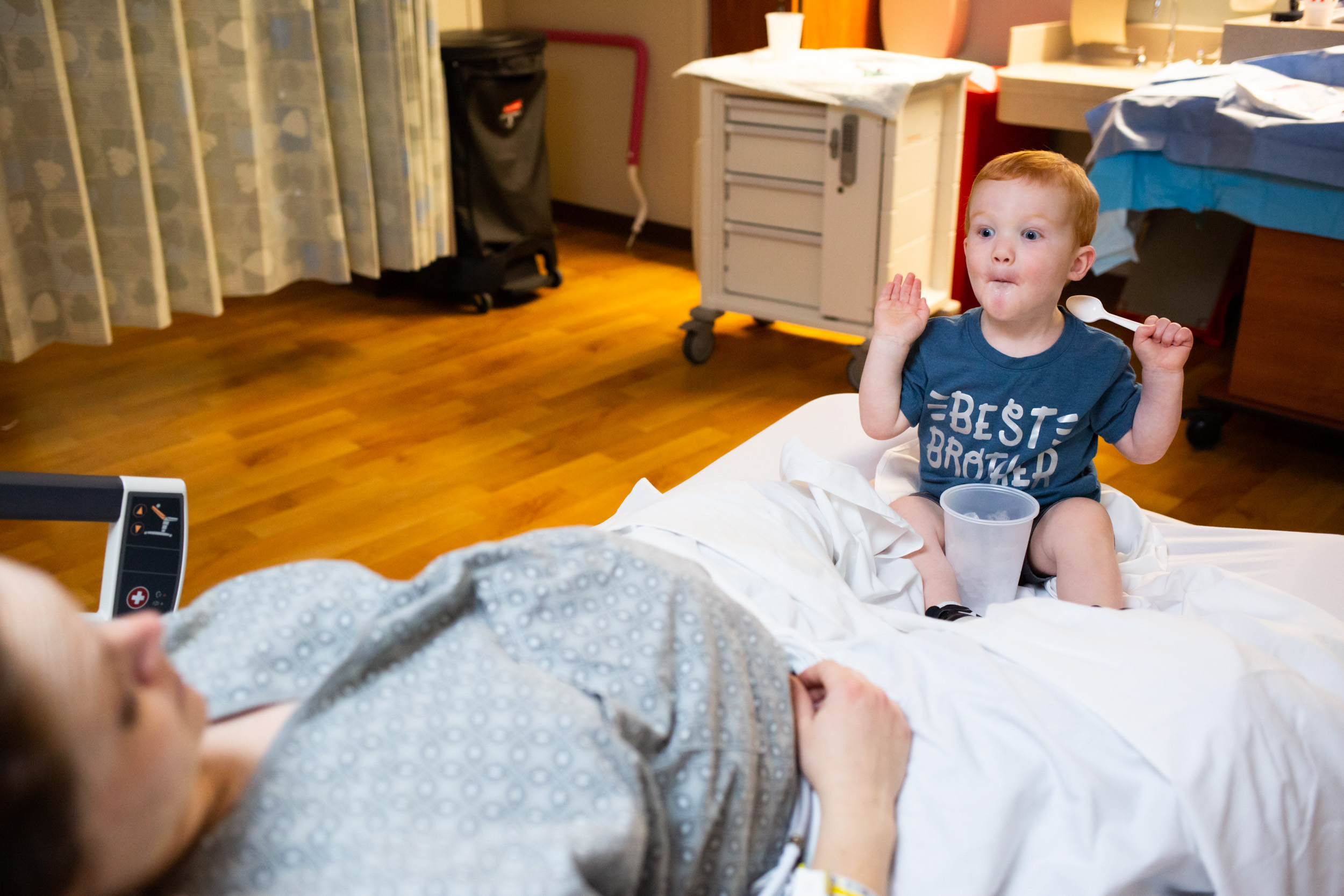 little boy making his mom laugh in hospital room during her labor