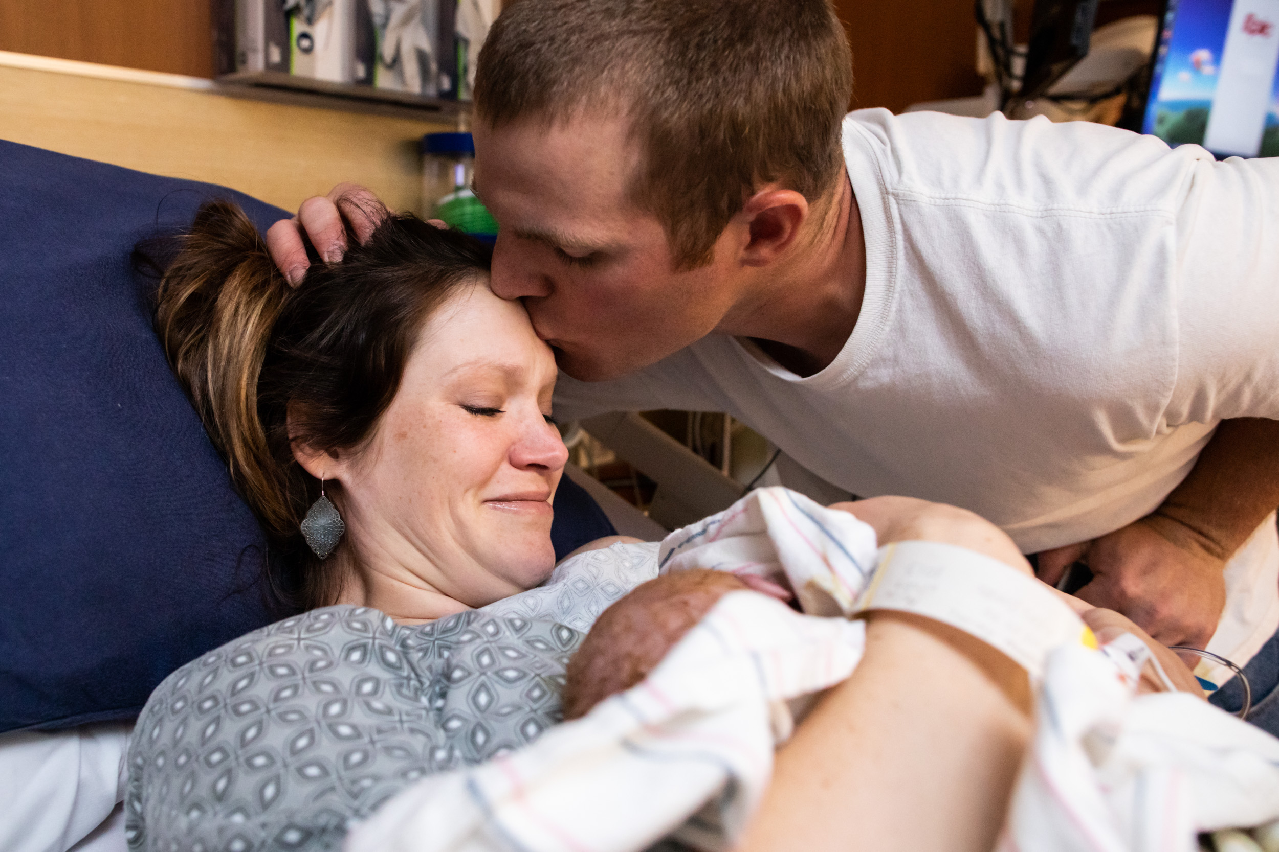 husband kissing wife after she birthed their son