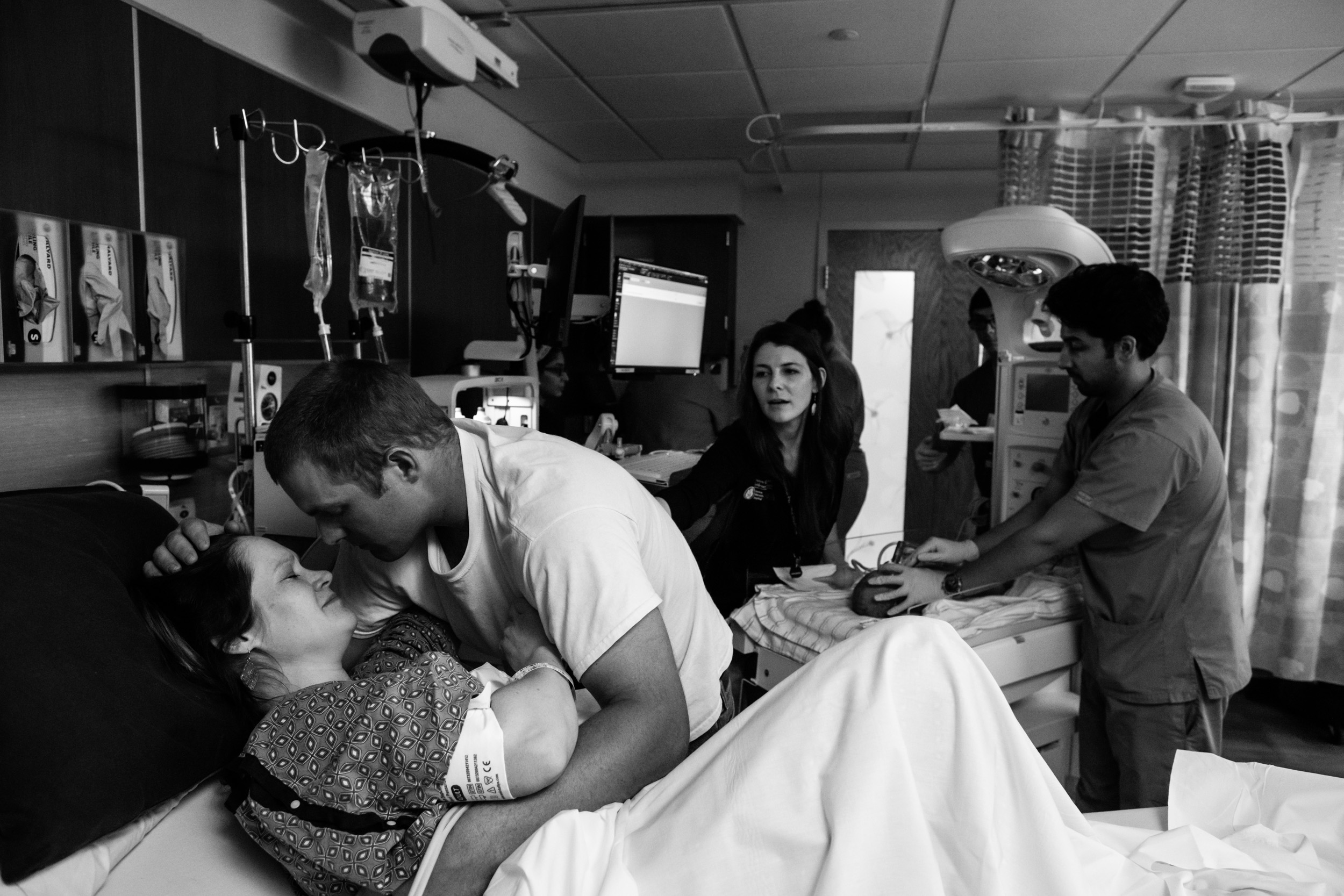 husband and wife comforting each other while baby being brought over so they could see him