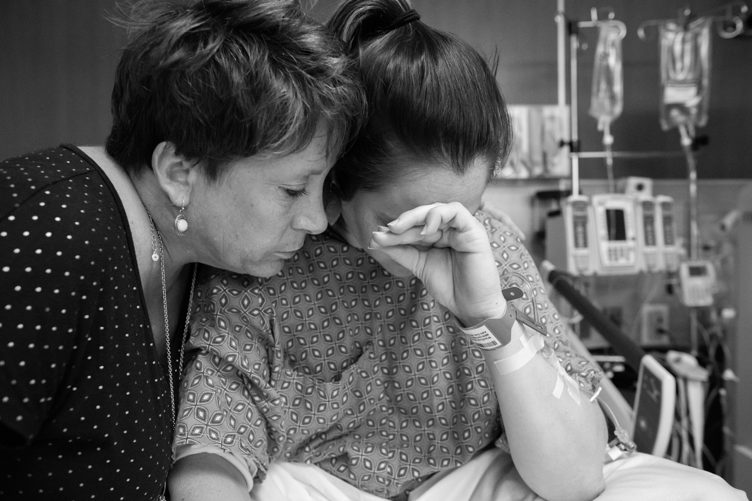 mom hugging daughter while crying due to her newborn baby being taken to the nicu