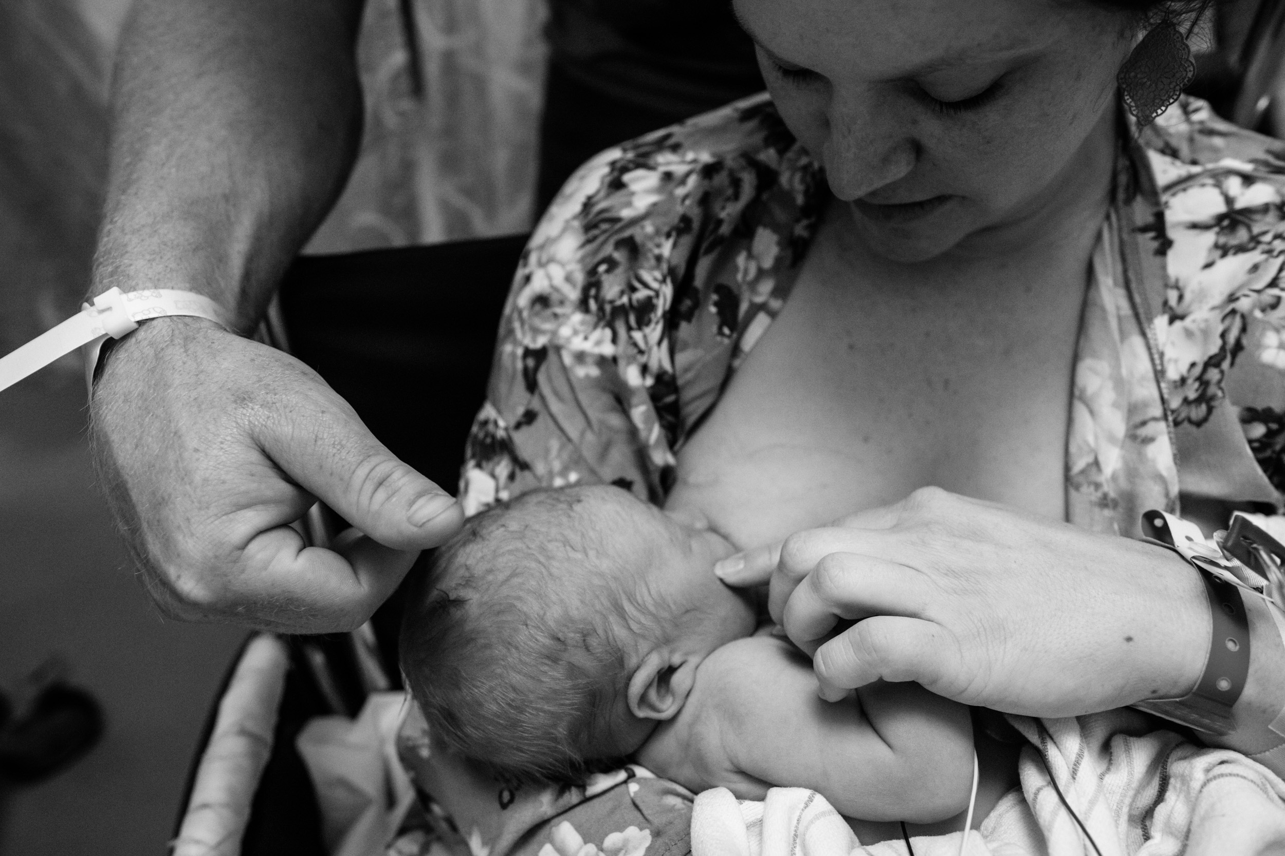 dad touching his newborn baby's head while mom breastfeeds