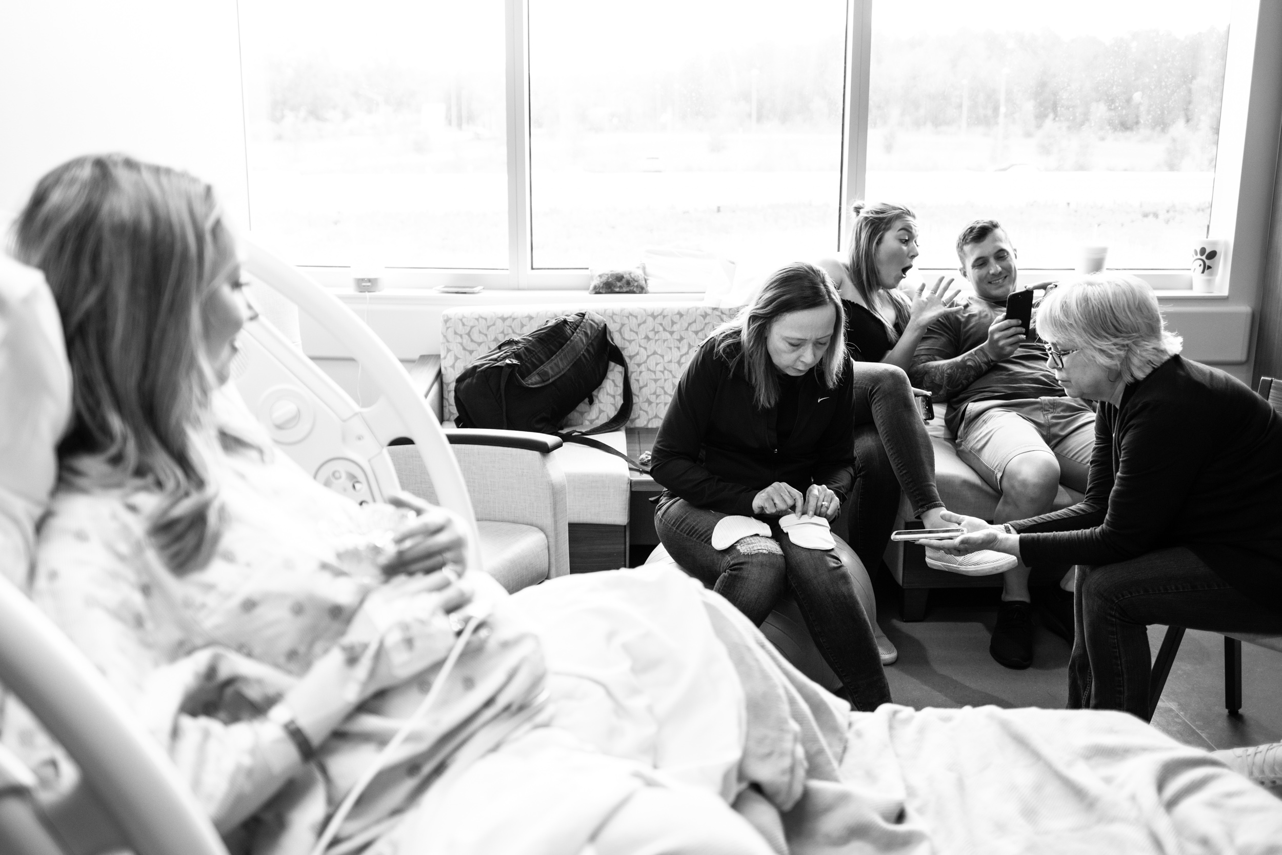 hospital room with family preparing a newborn hat with a bow