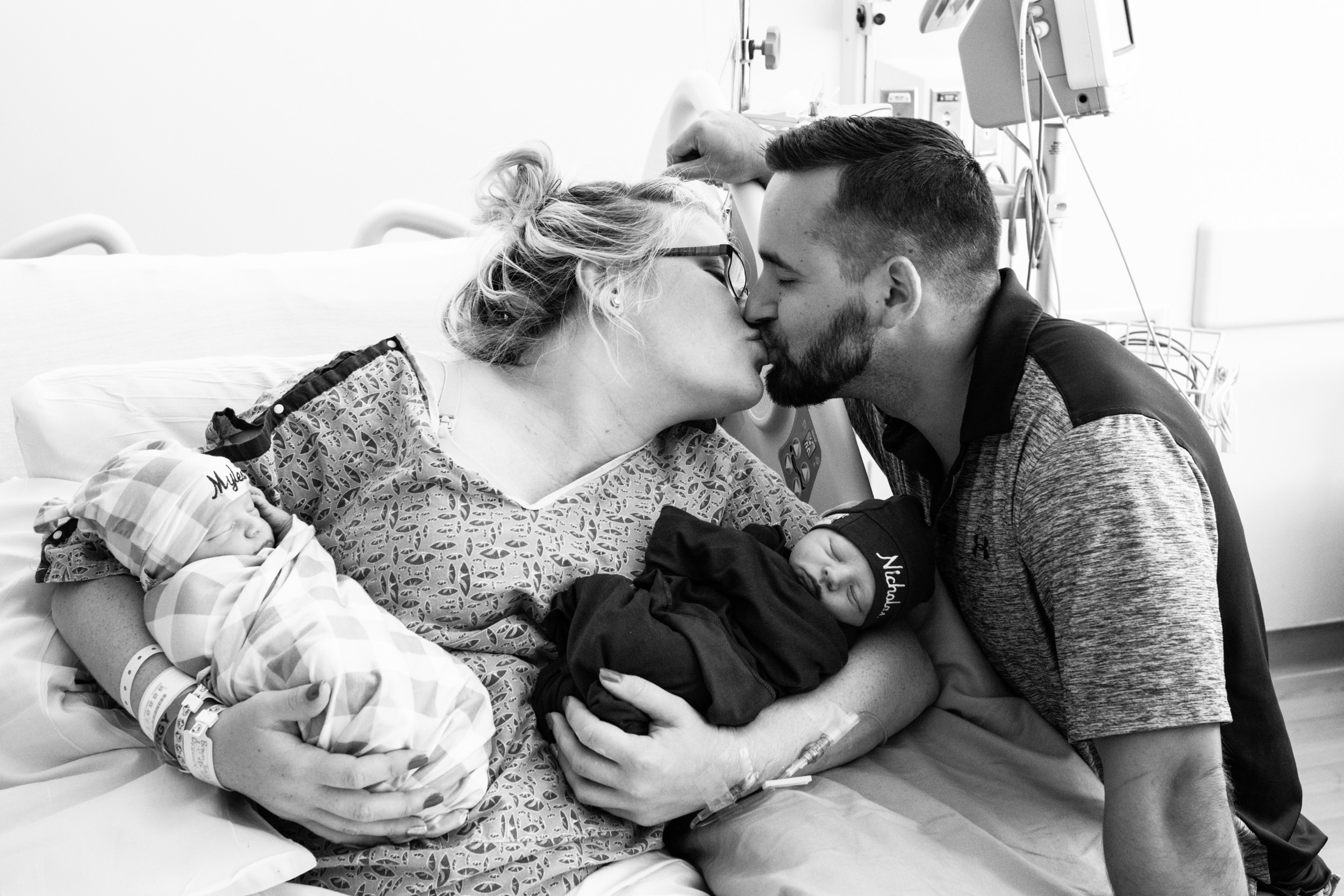 jacksonville twin parents kissing while holding newborn babies