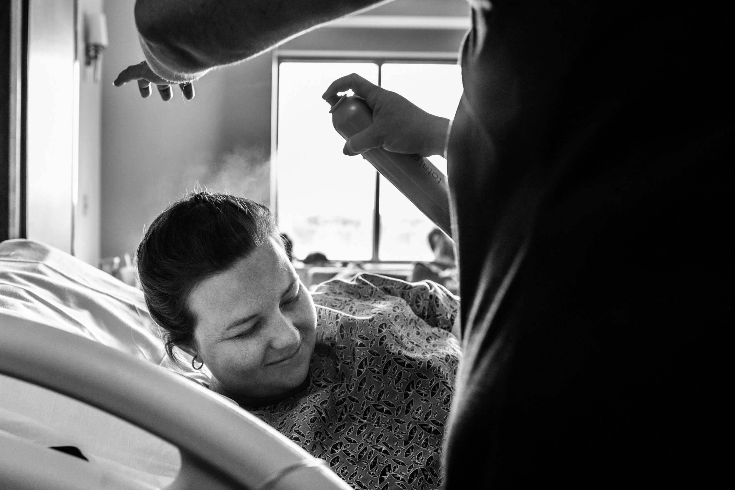 laboring mom in hospital bed getting hair fixed