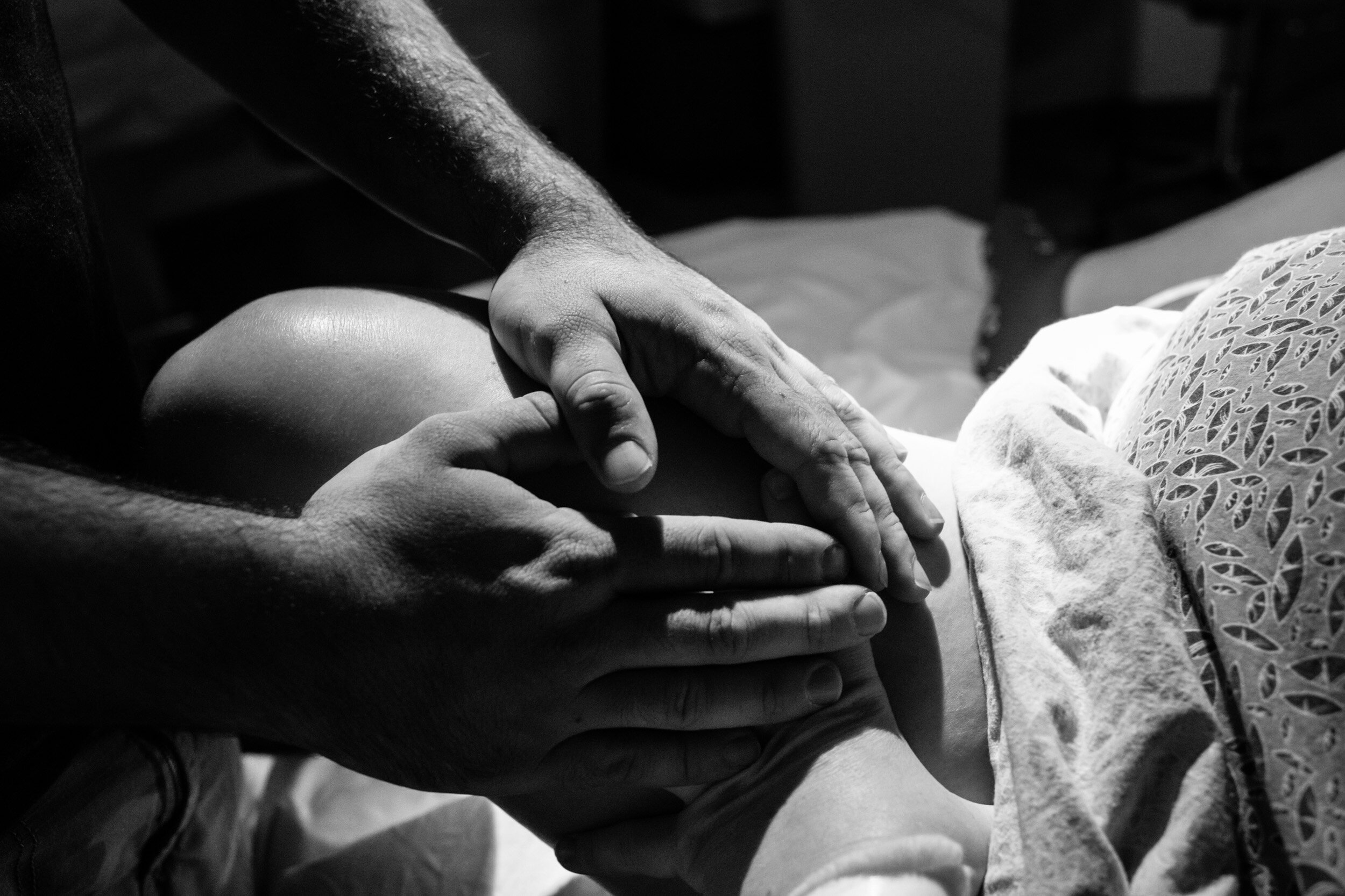 new dad putting his hands over his wife hand as she labors