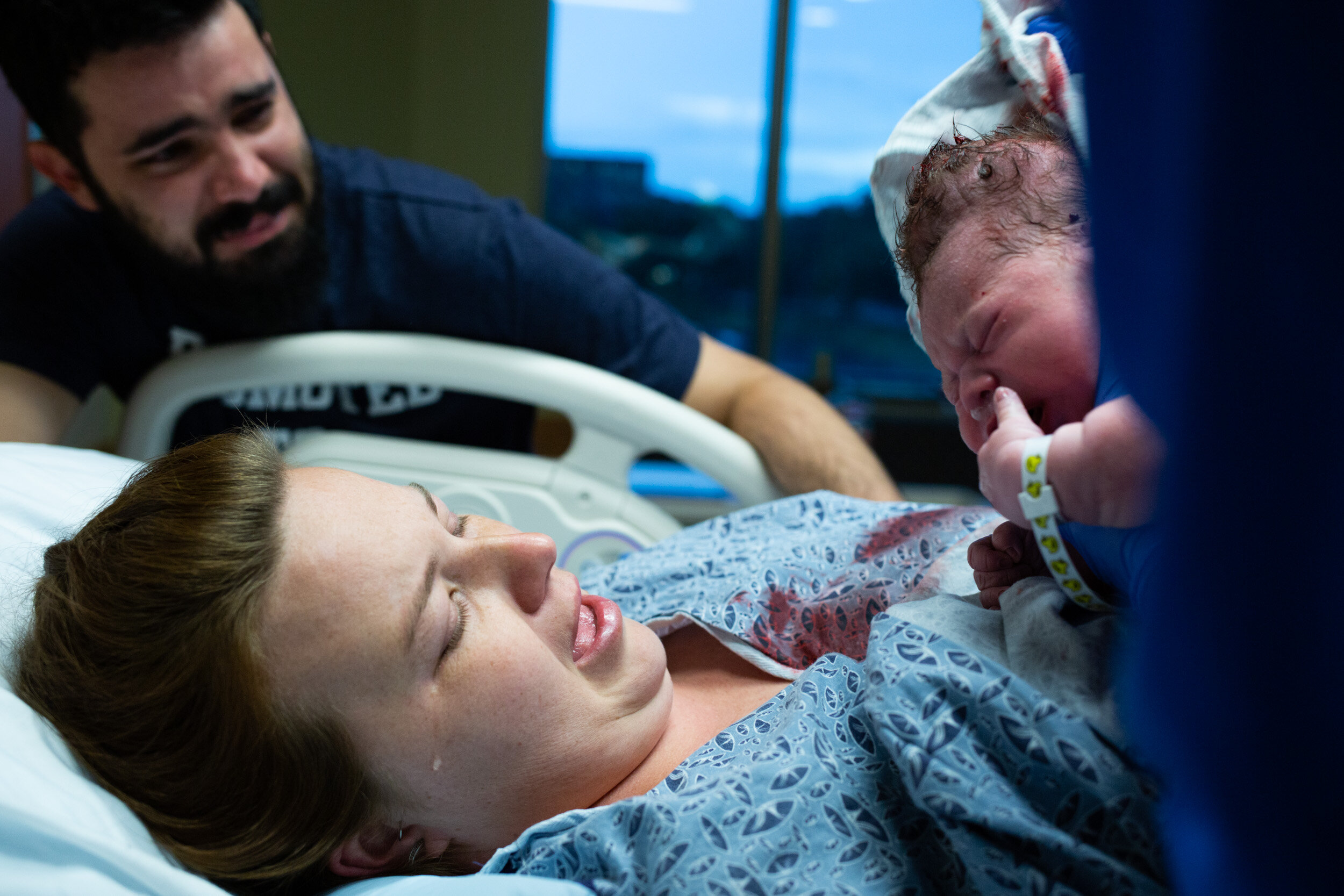 new mom with tear dripping down her face as she holds her newborn baby boy