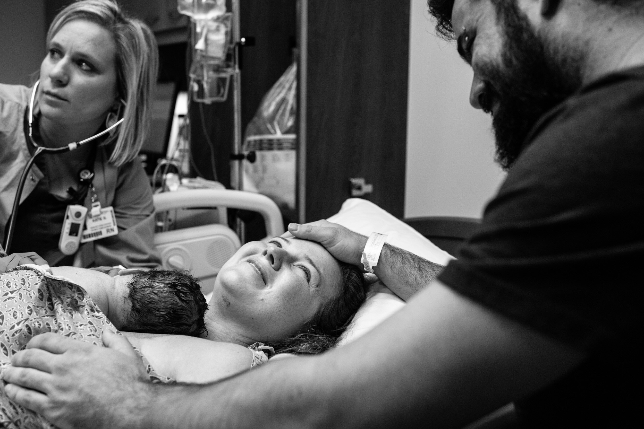 new mom looking sweetly at her husband as they hold their newborn baby boy