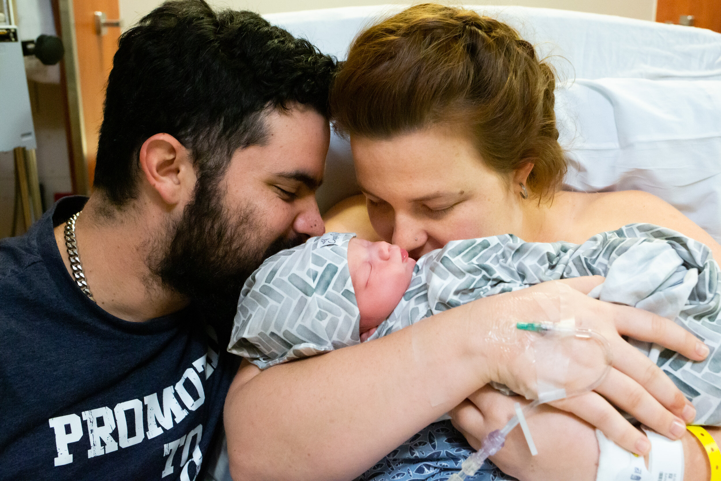 parents kissing their newborn baby boy