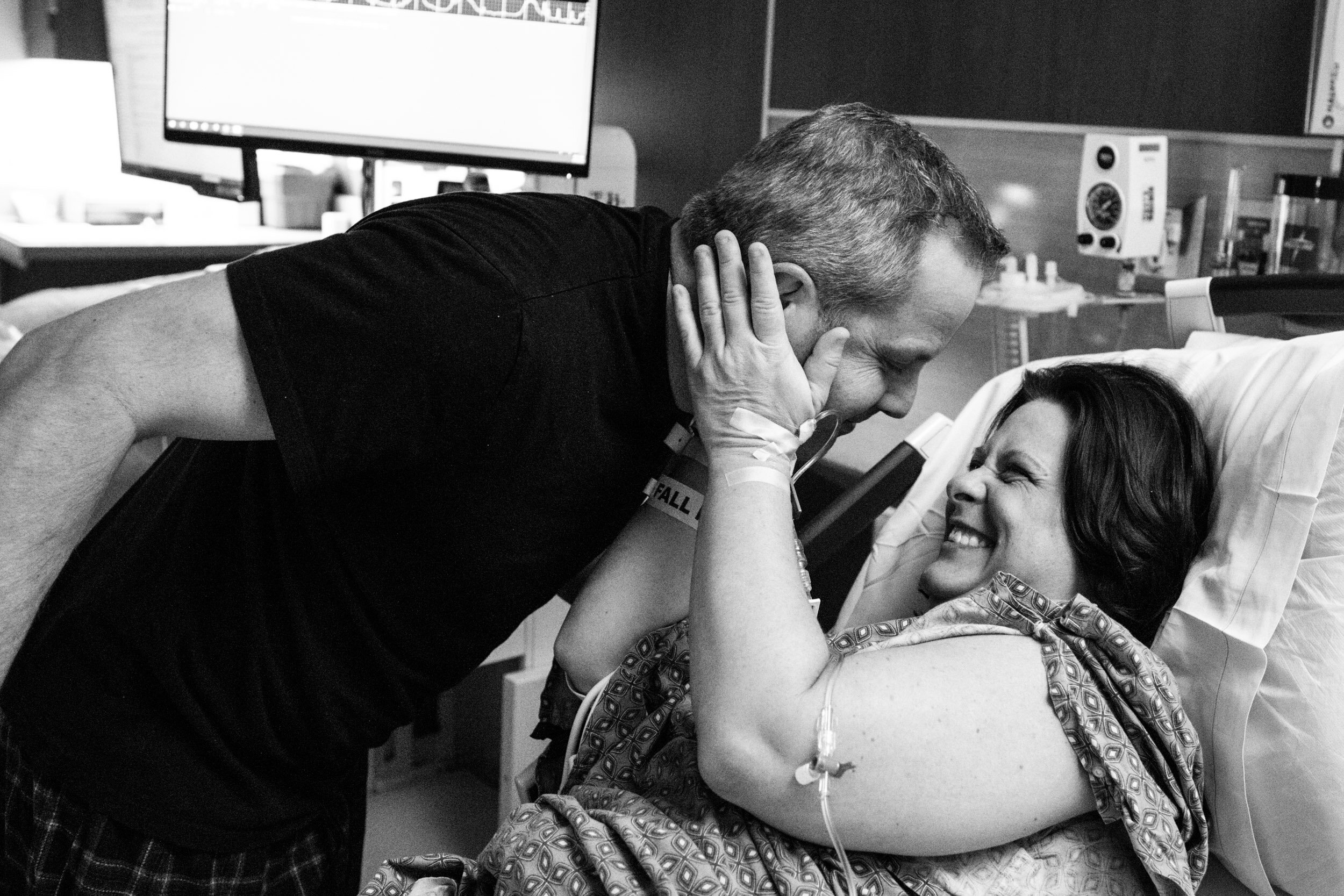 wife holding husband's face and laughing while waiting for birth