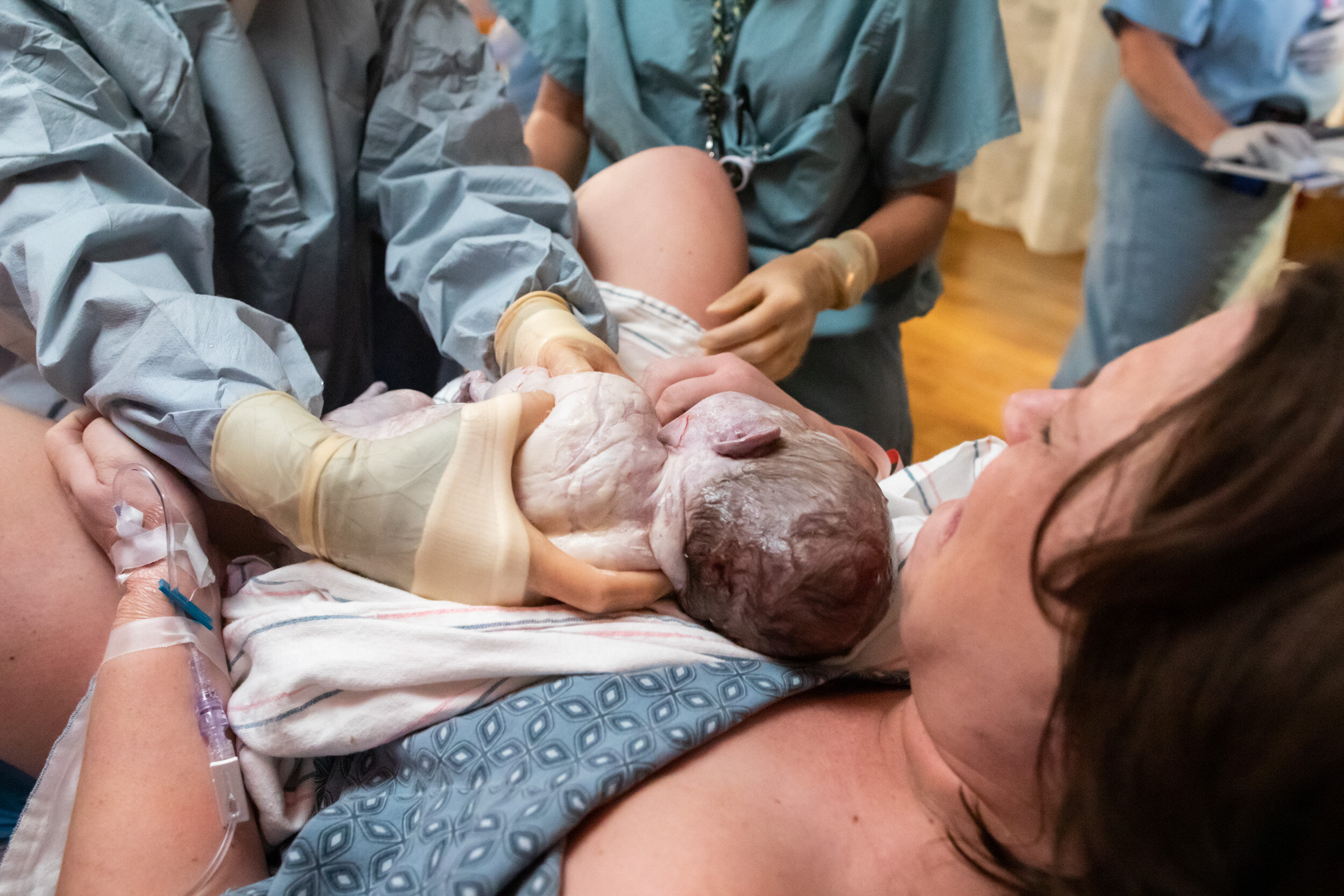 newborn baby just after birth being placed onto mom's chest