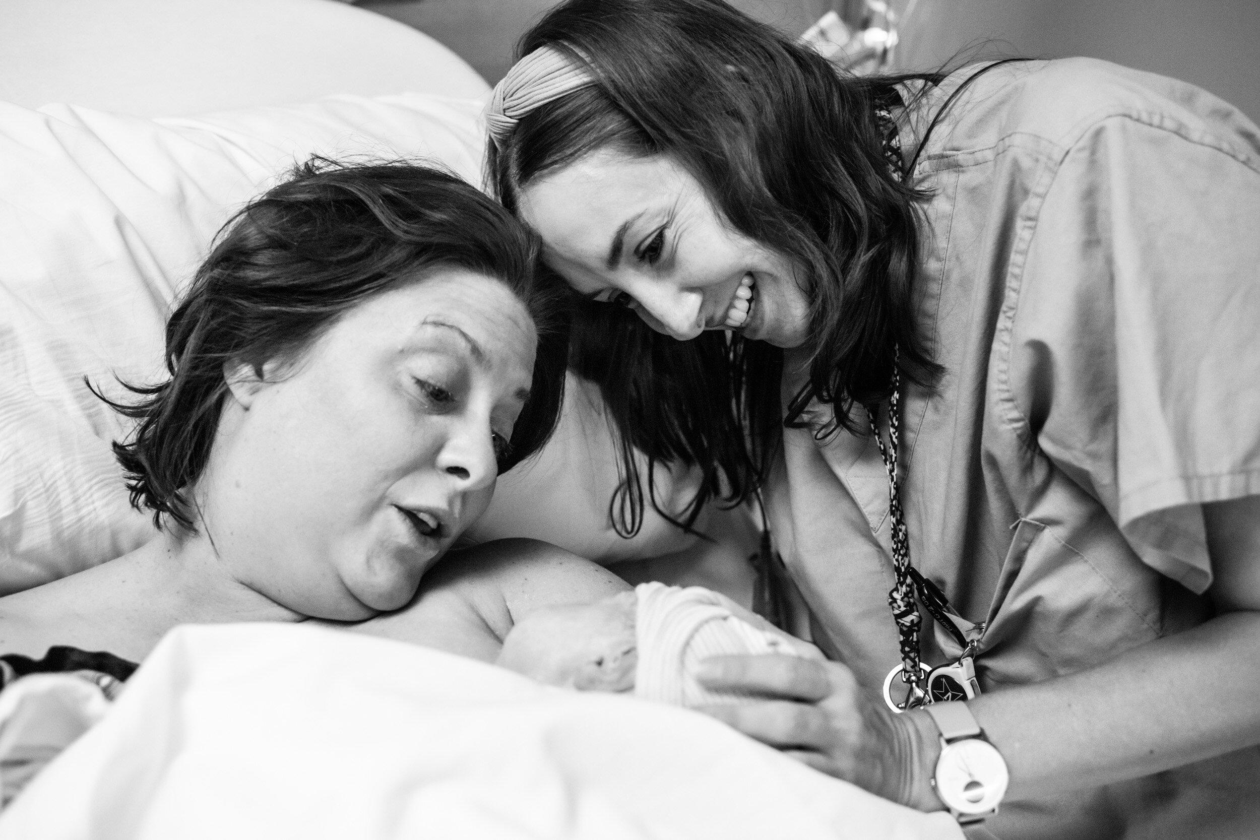 midwife admiring newborn baby with new mom