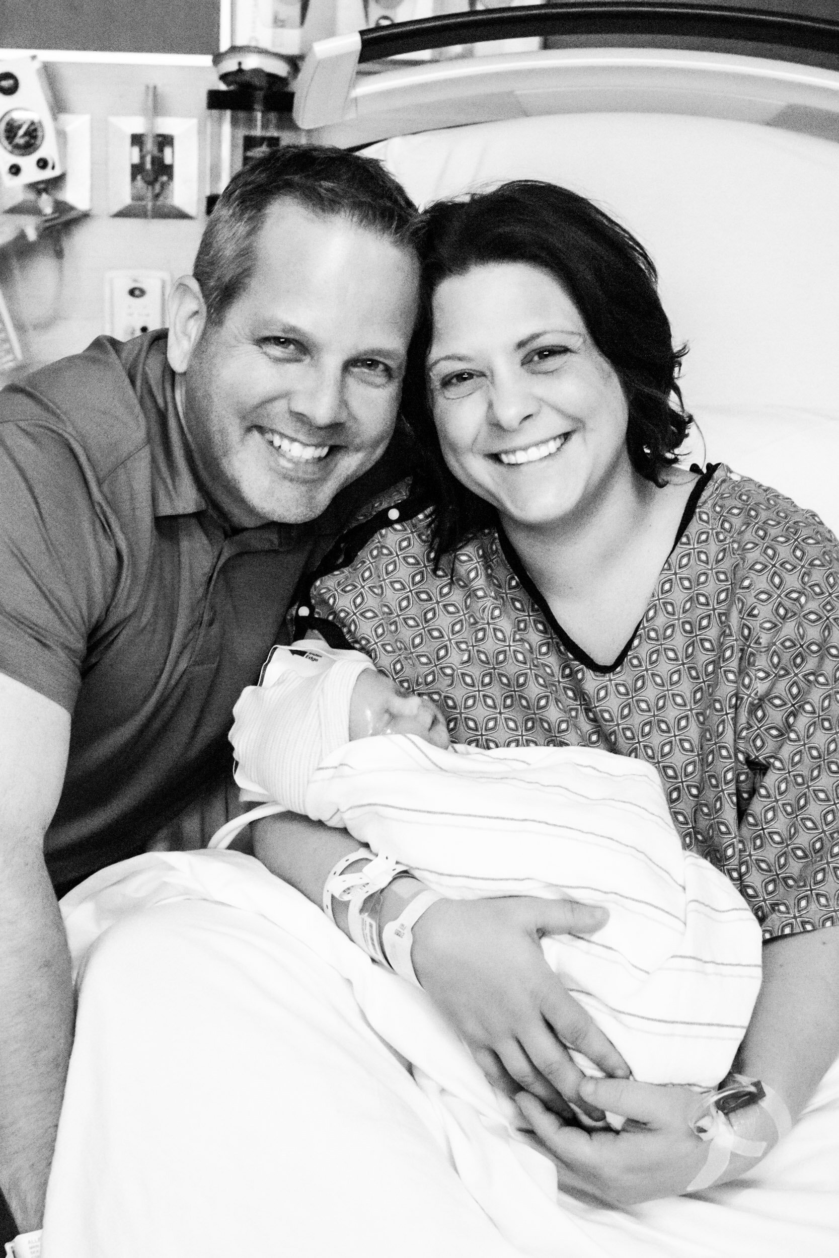 new parents smiling with their baby girl just after birth