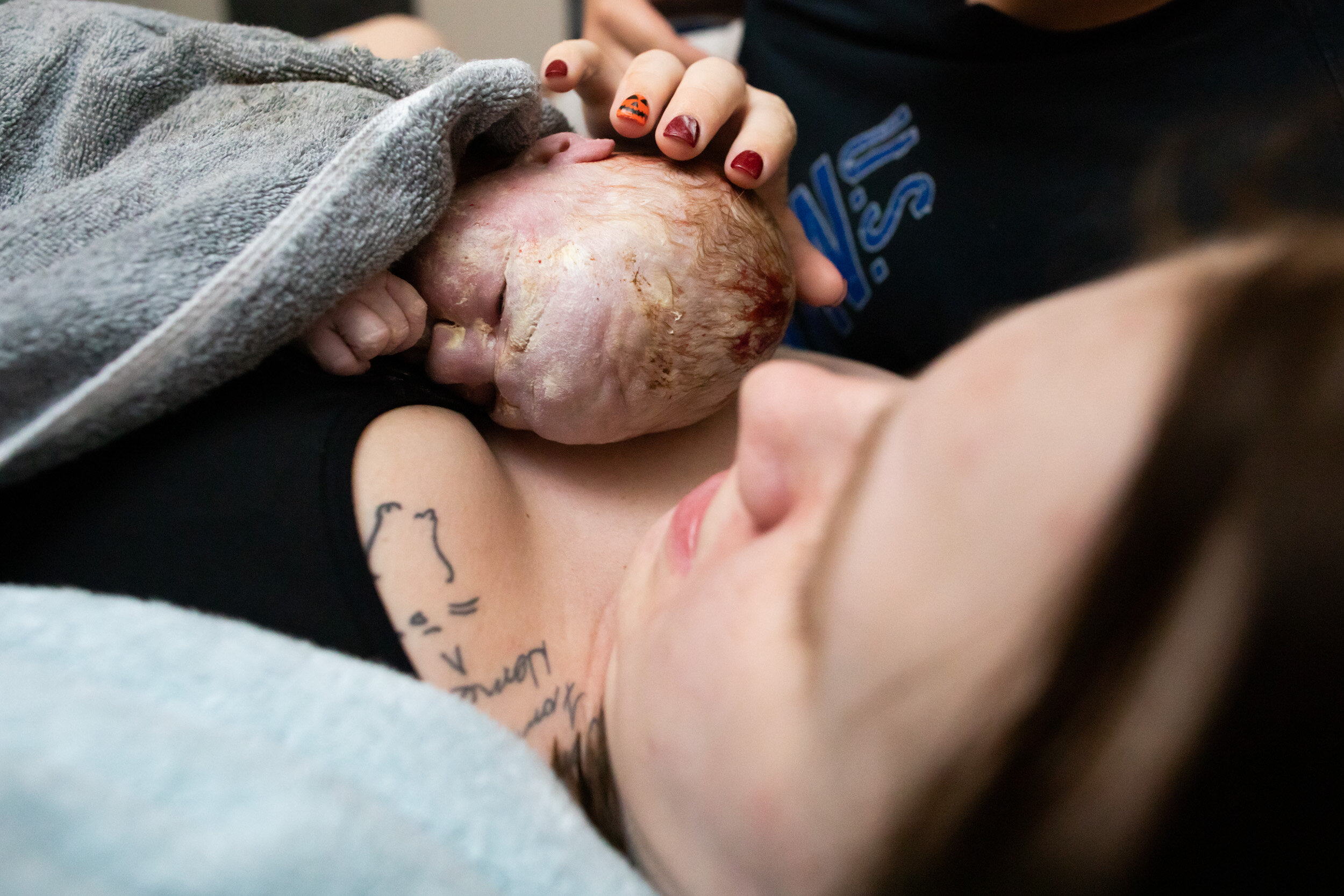 new mom touching the head of her baby girl just after birth