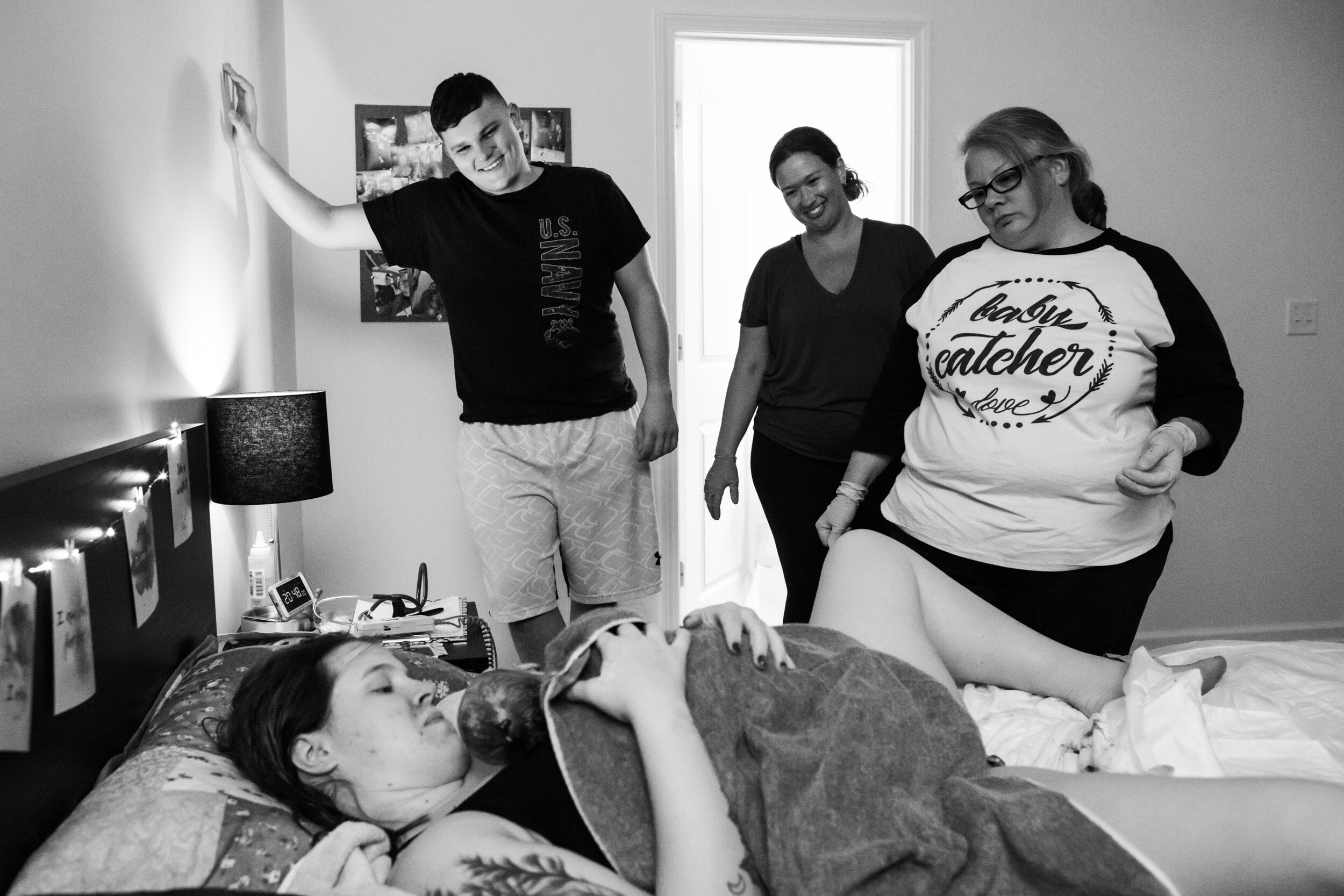 midwives and new dad look on as mom holds her newborn baby girl