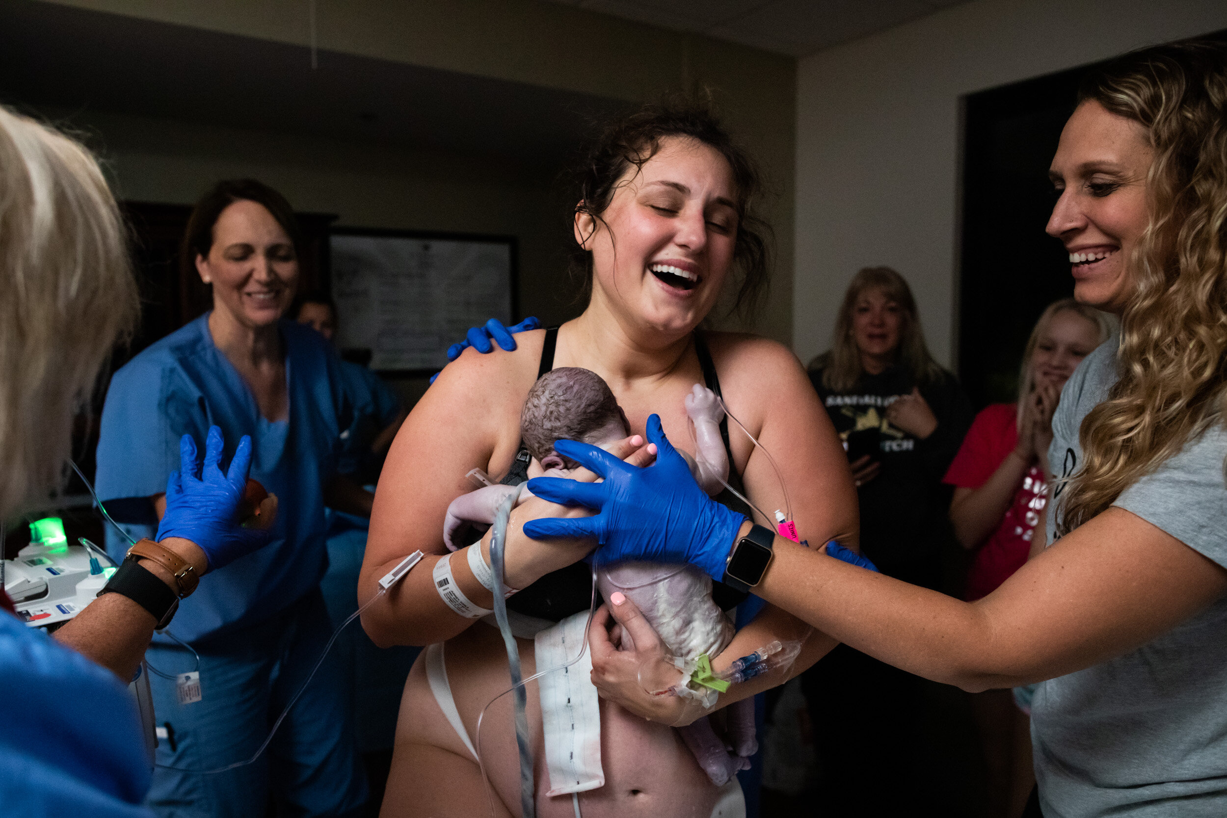 jacksonville mom laughing with joy holding her newborn baby boy just after birth