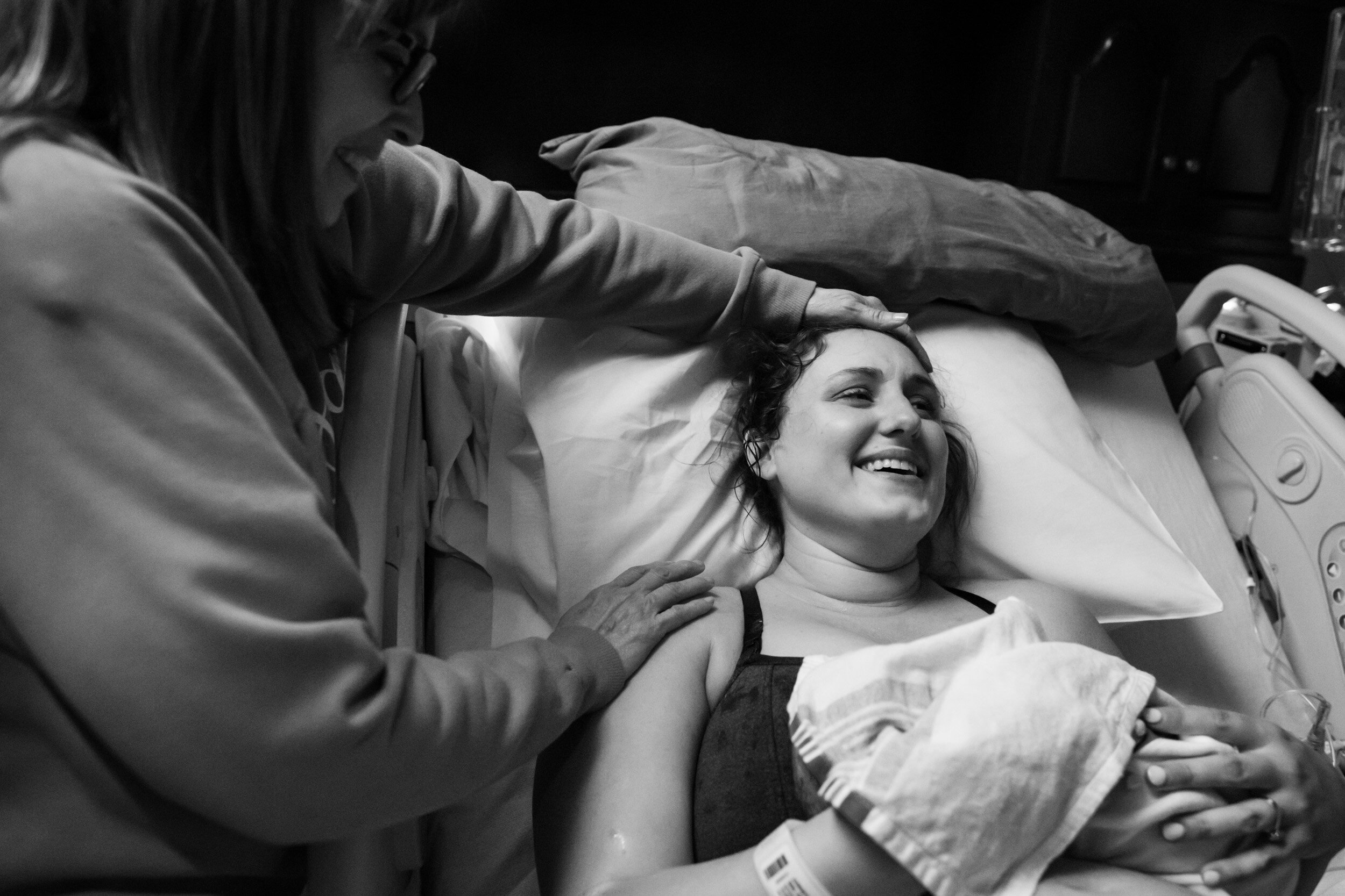 new mom smiling while holding her baby after birth