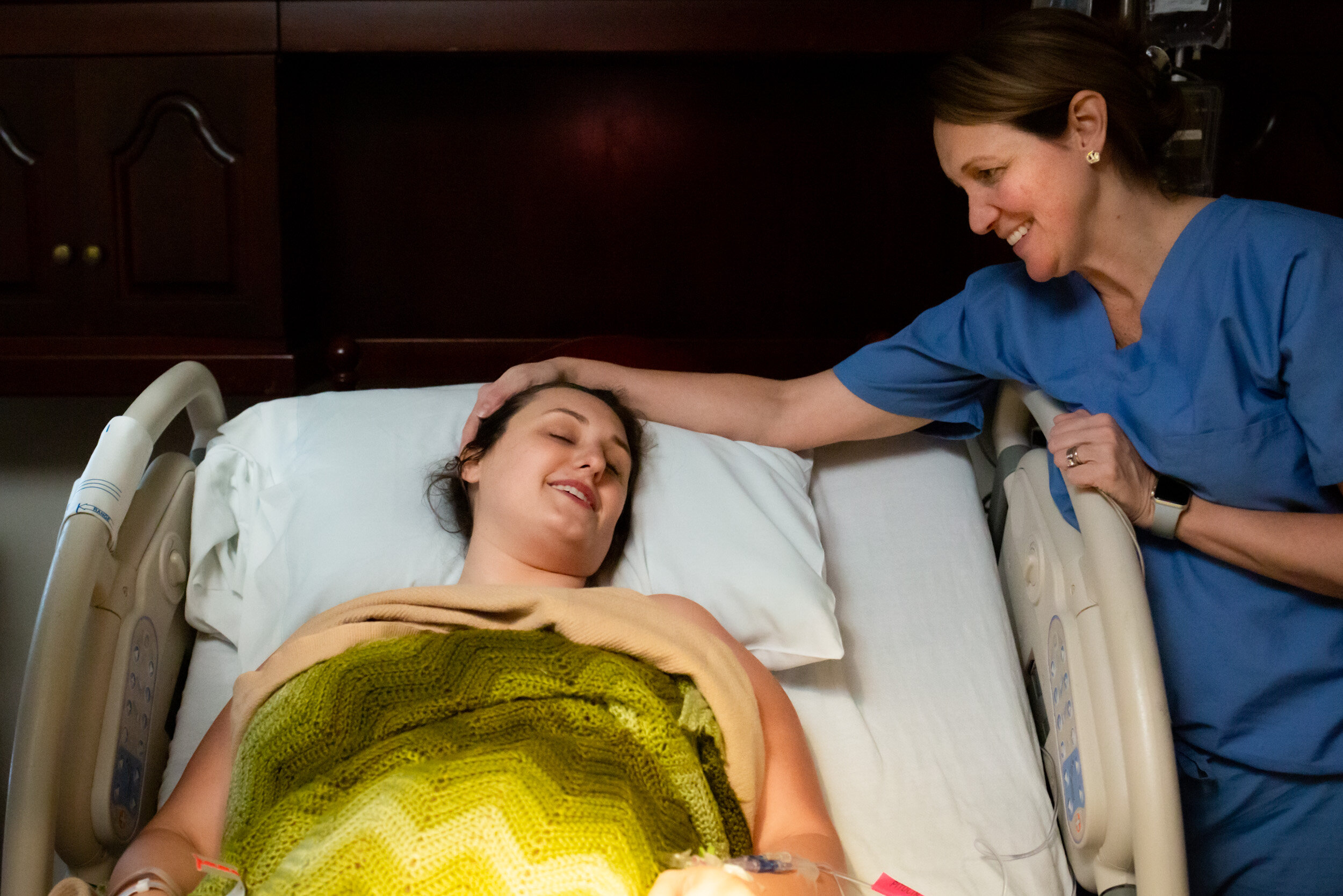 midwife with hand on mom's head after birth, looking at her new baby
