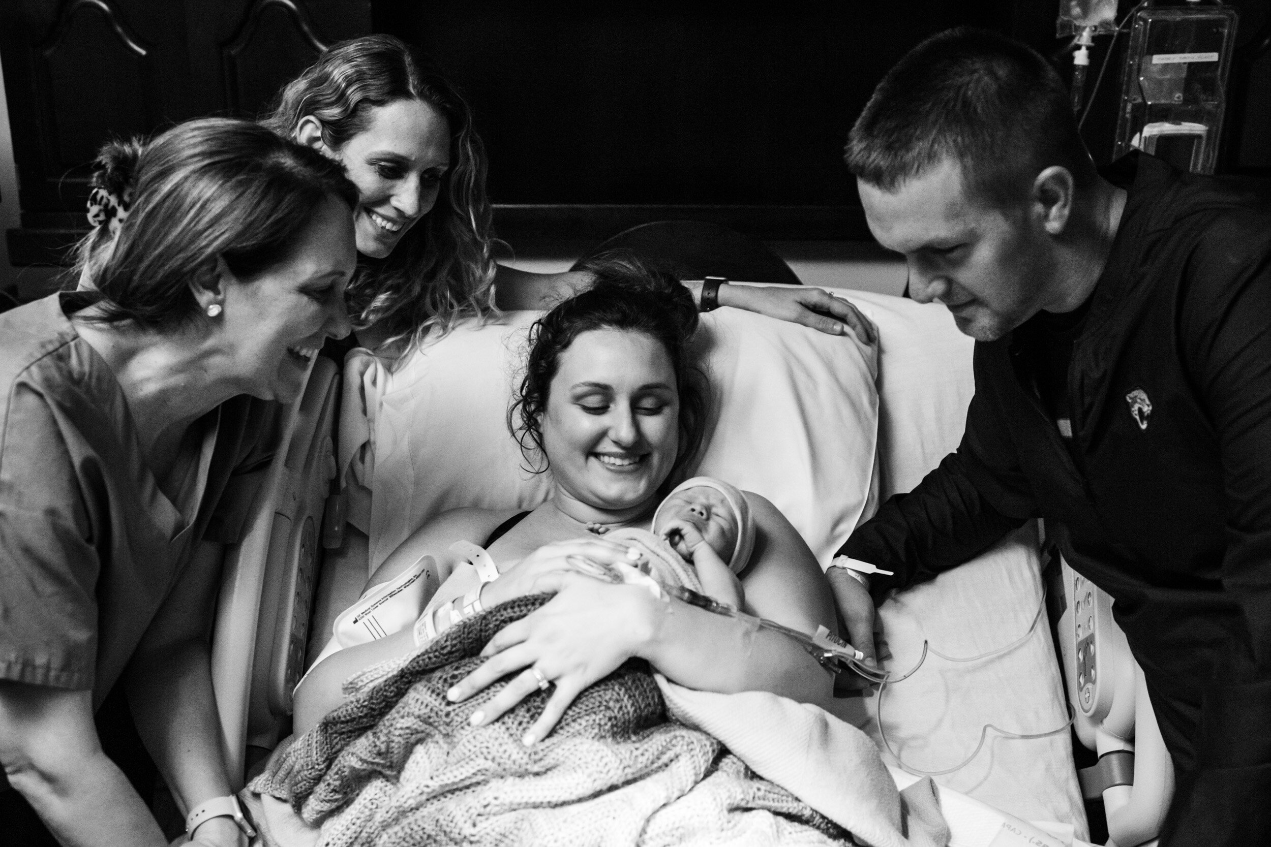doula and family surrounding new mom and baby