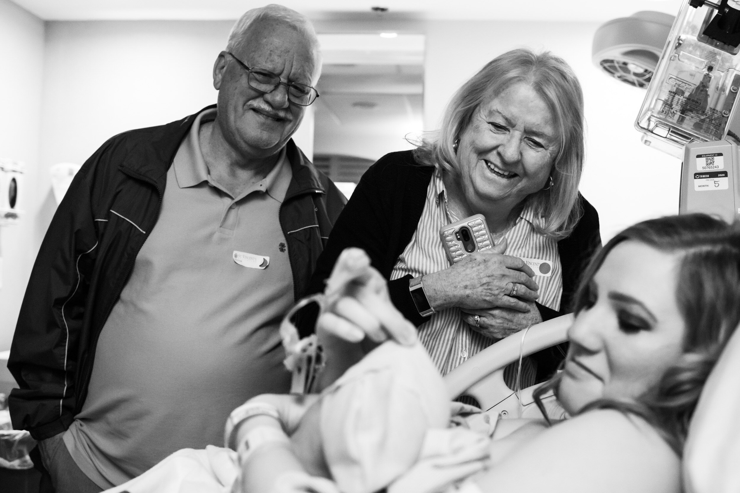 great-grandparents smiling while looking at their newborn grandson