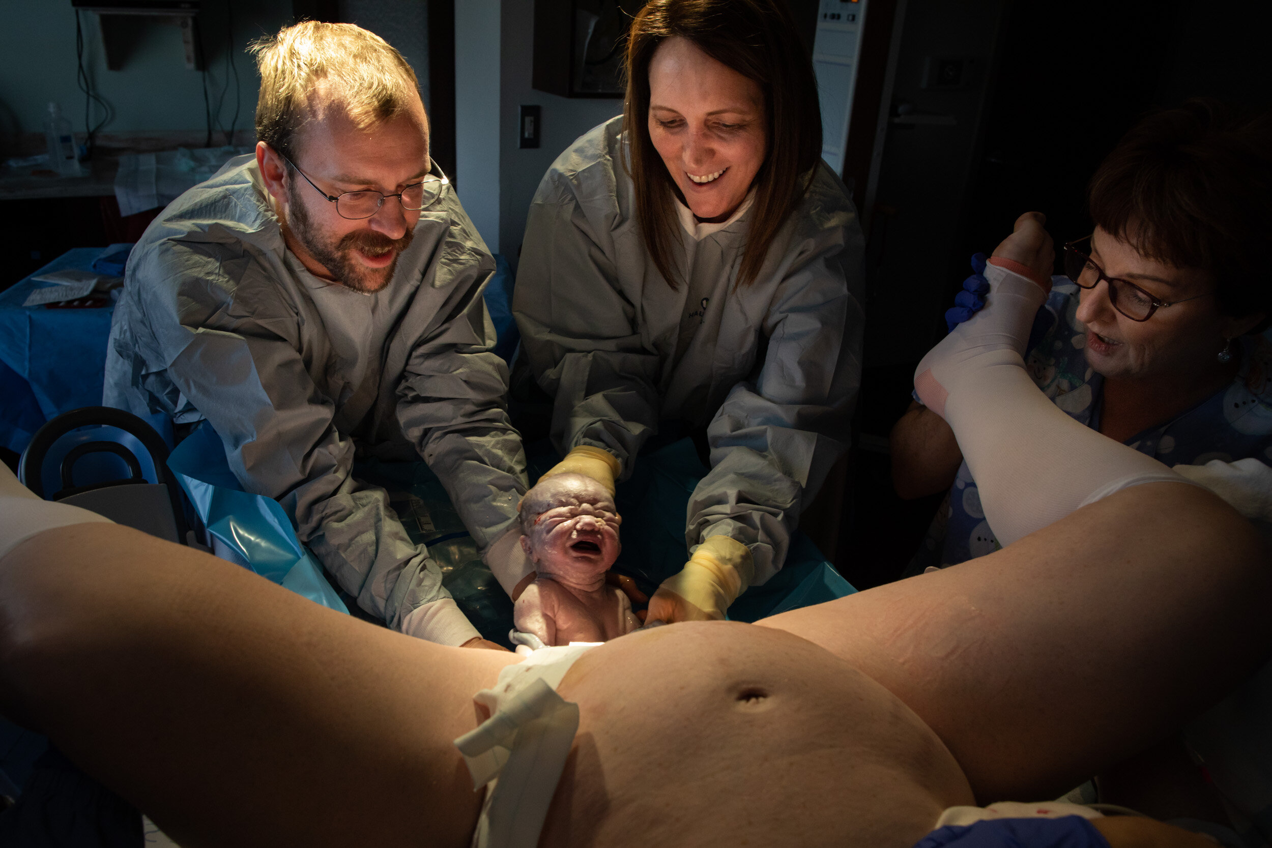 baby being born into the hands of his dad and midwife