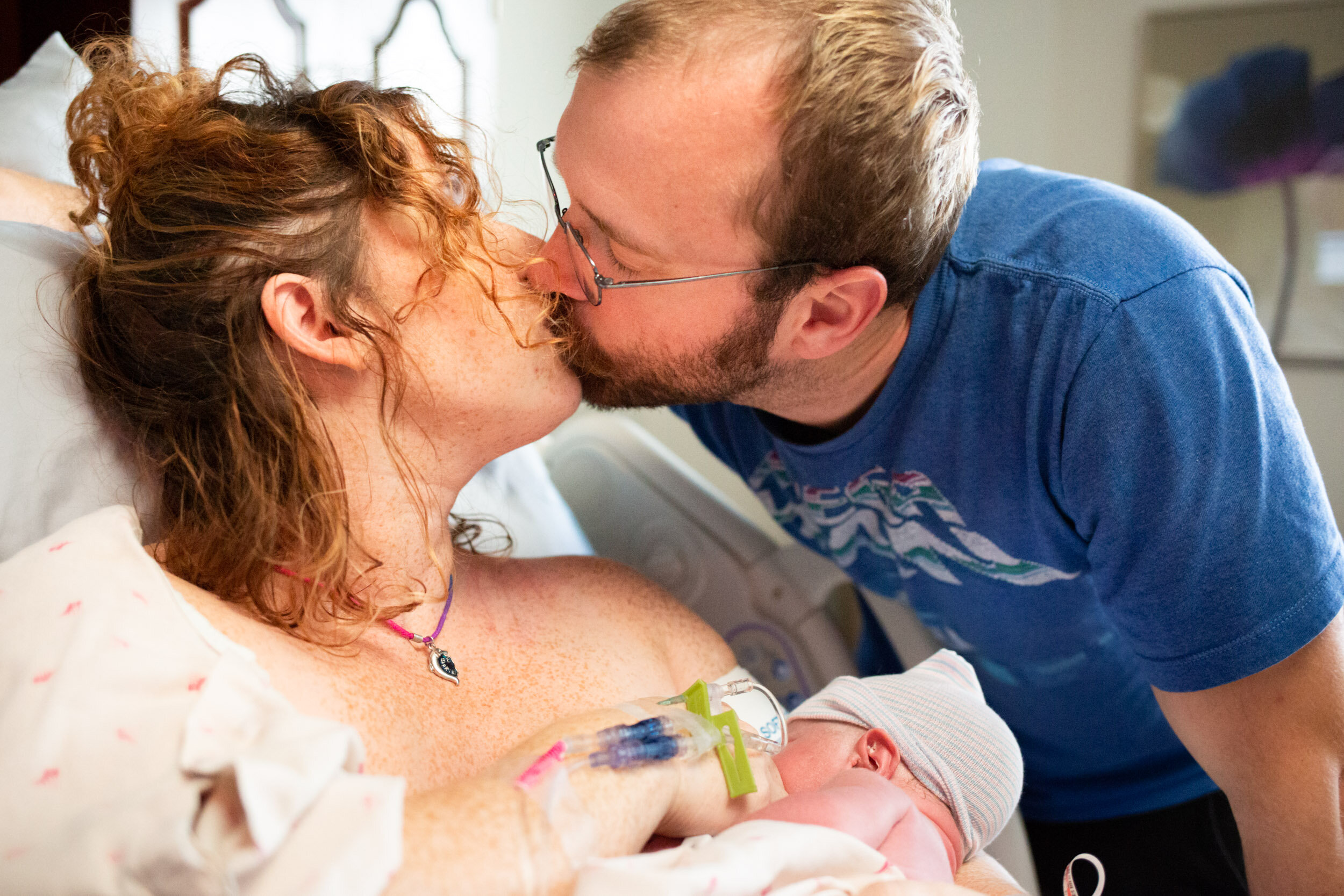 jacksonville parents kissing while holding their newborn baby boy