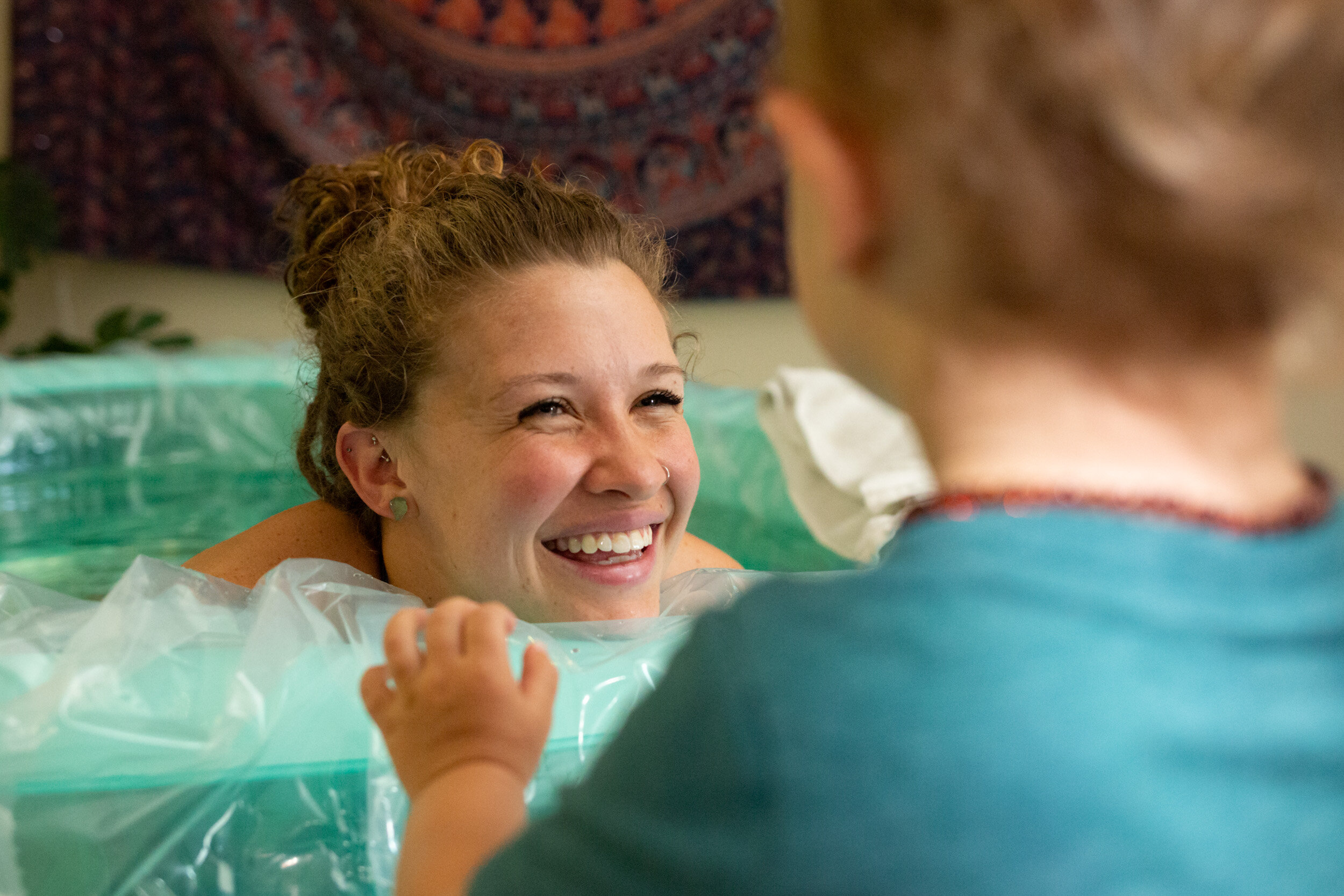 birth mom smiling at her toddler son while in birthing pool