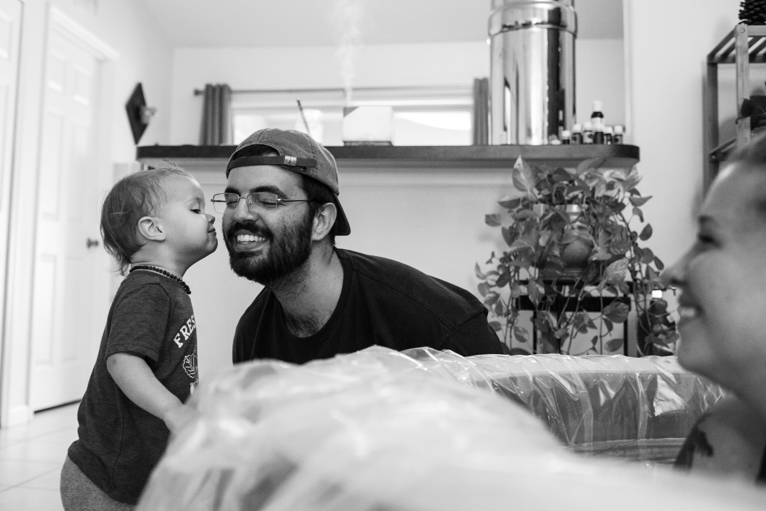 little boy kissing his dad on the cheek while mom looks on from birthing pool