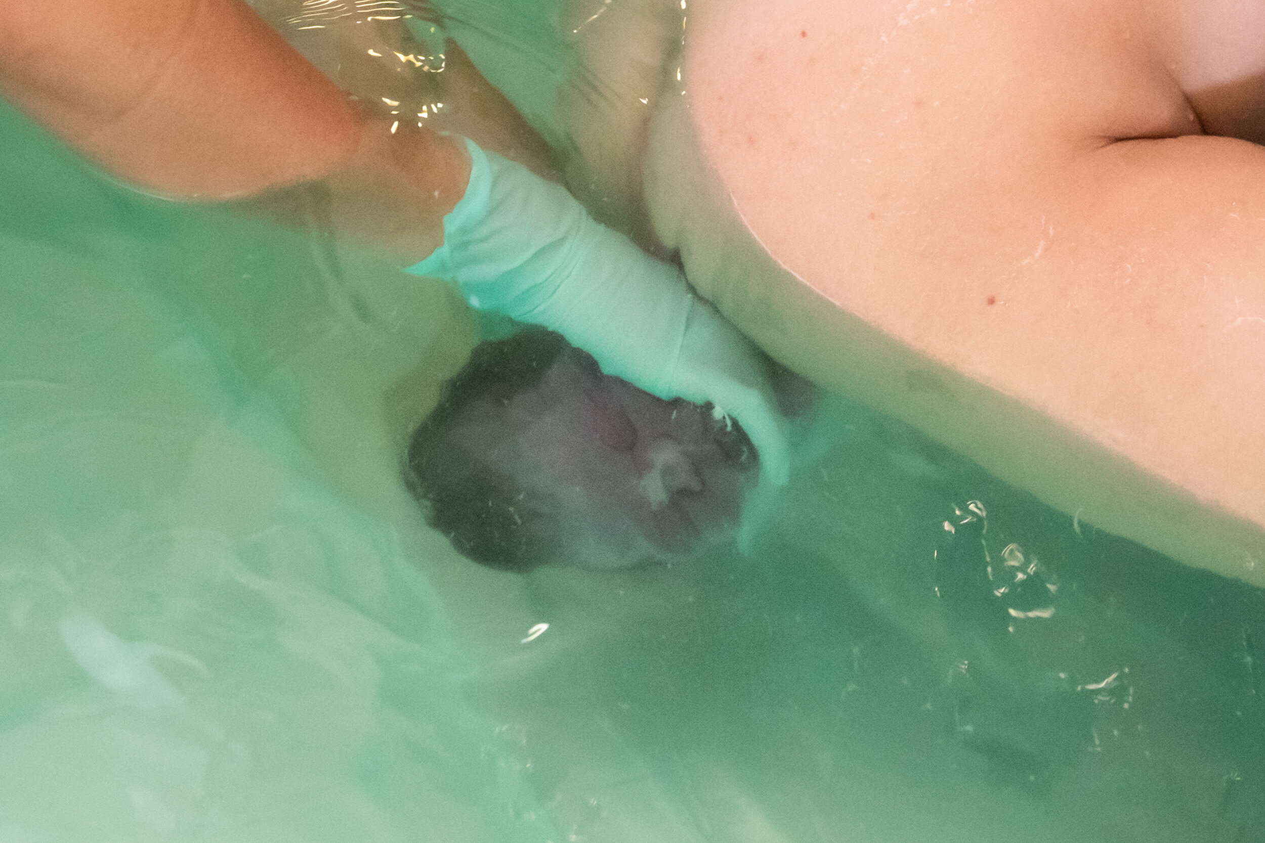 baby being born into the water in a birthing pool