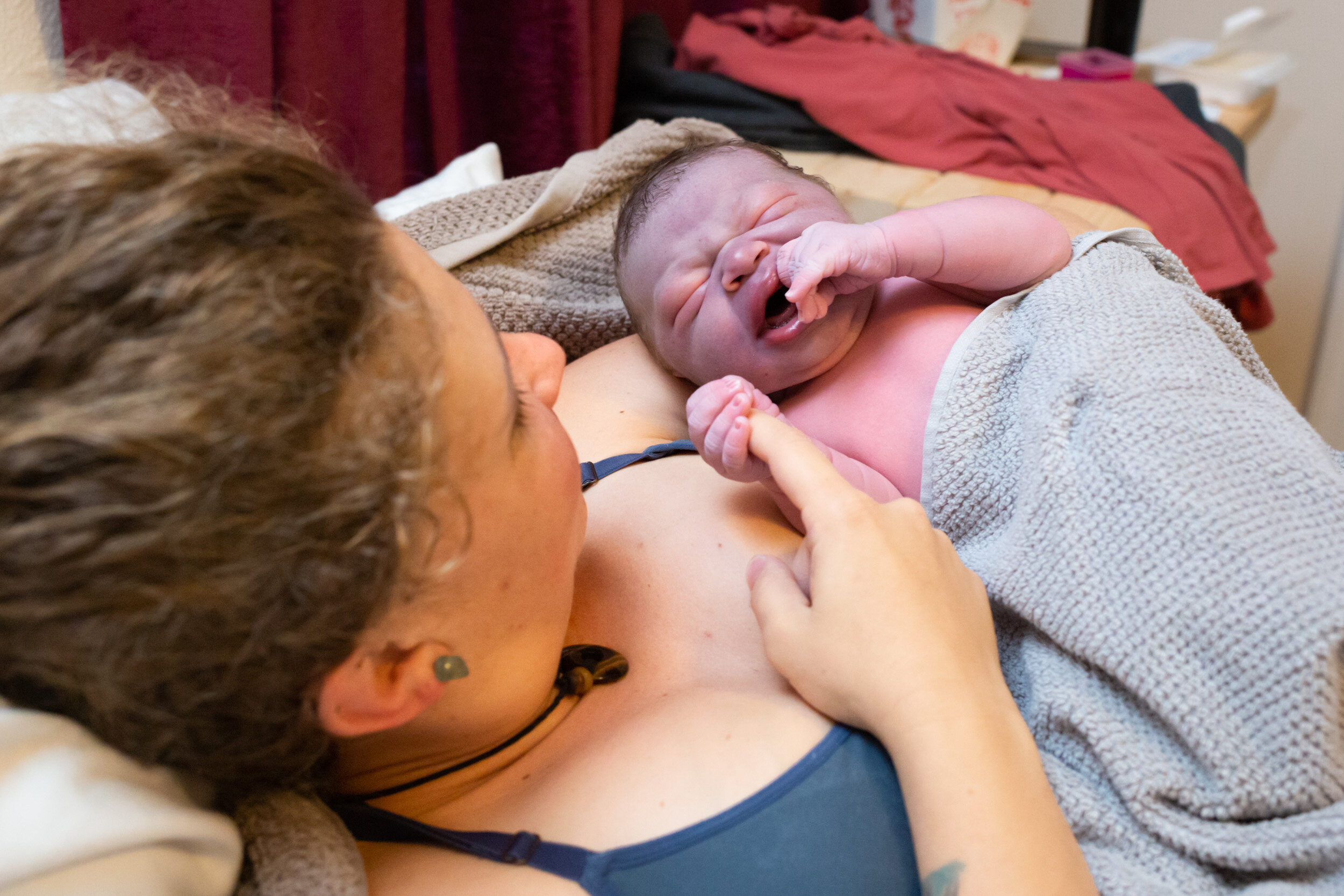 newborn baby holding his mom's finger