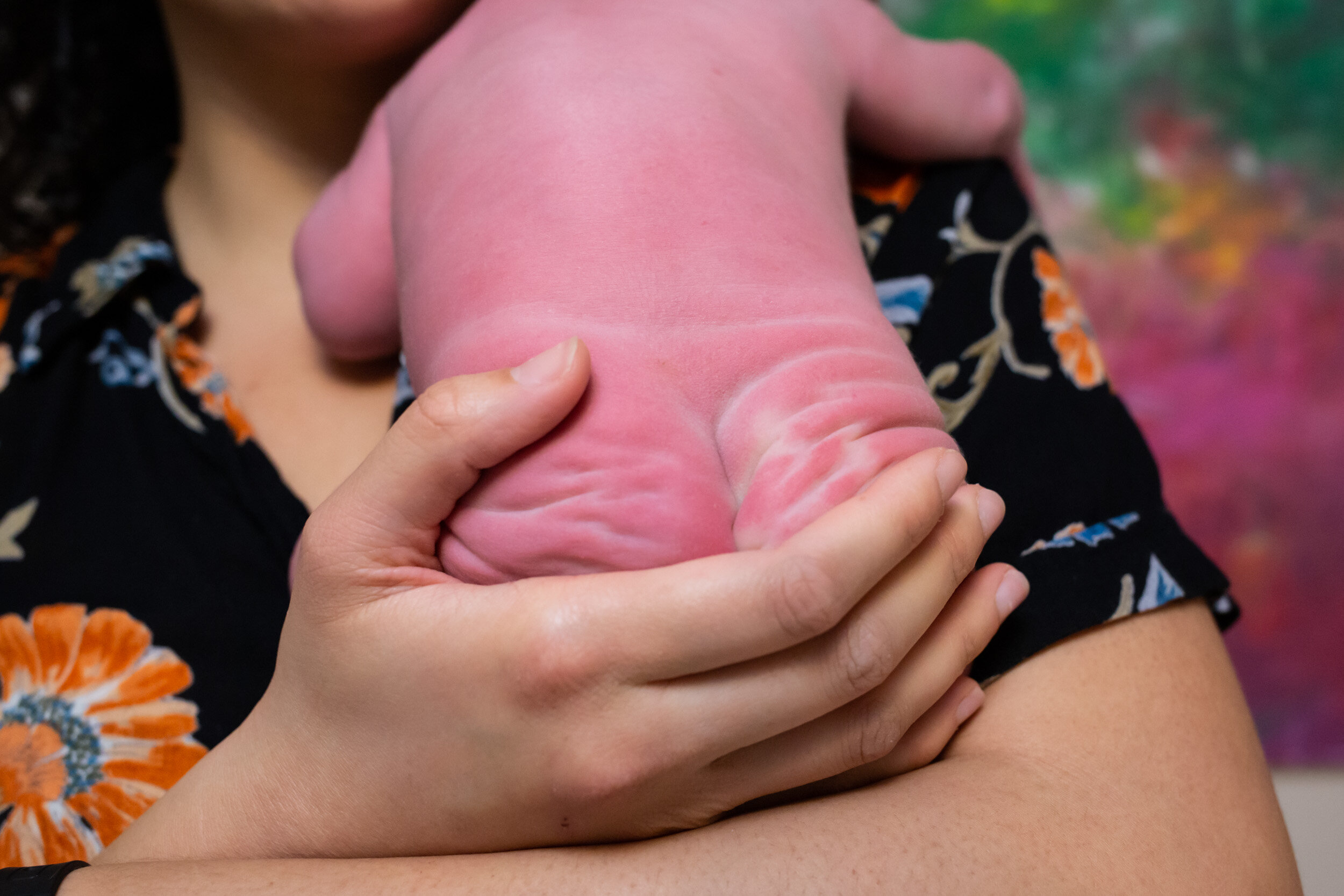 midwife holding baby with his wrinkly bottom featured