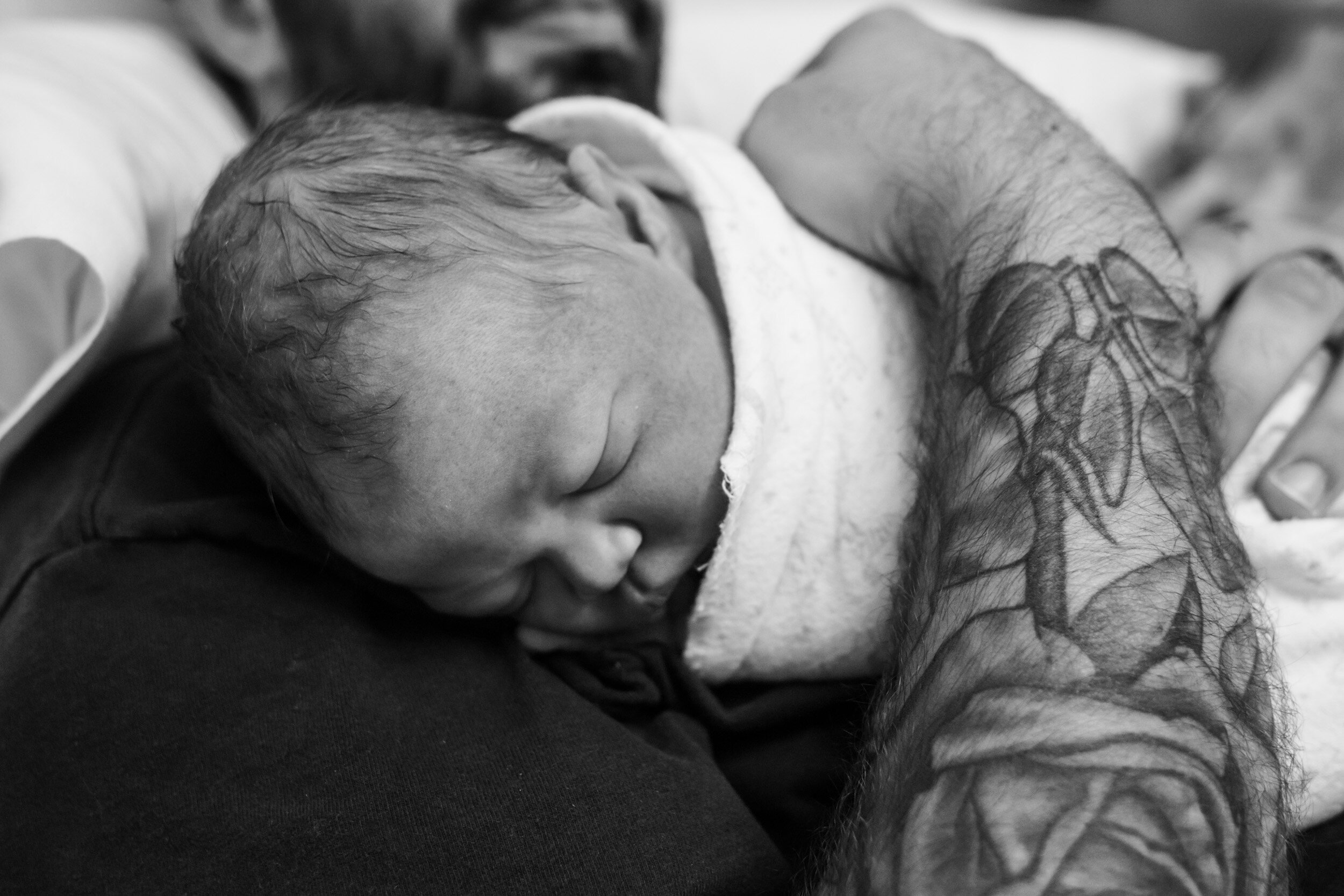 dad with tattoos holding newborn baby boy
