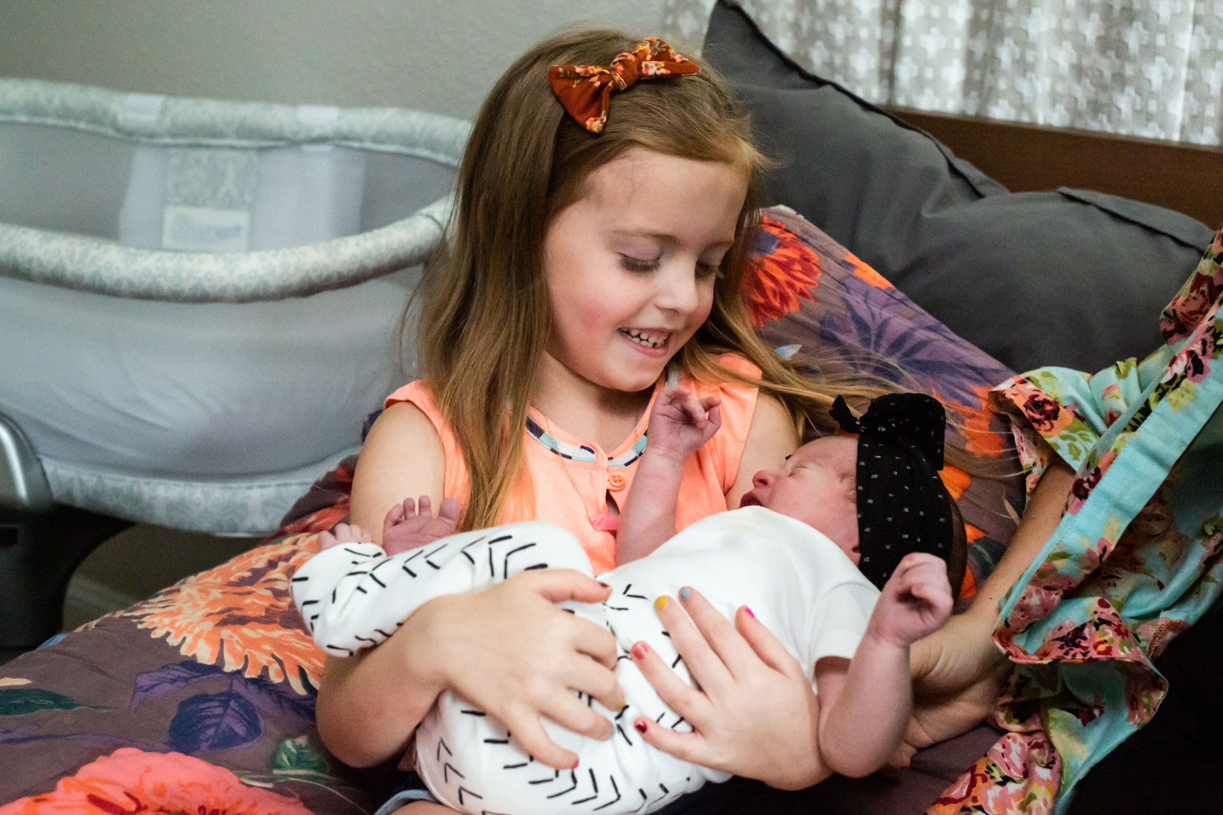 little girl smiling at her newborn baby sister