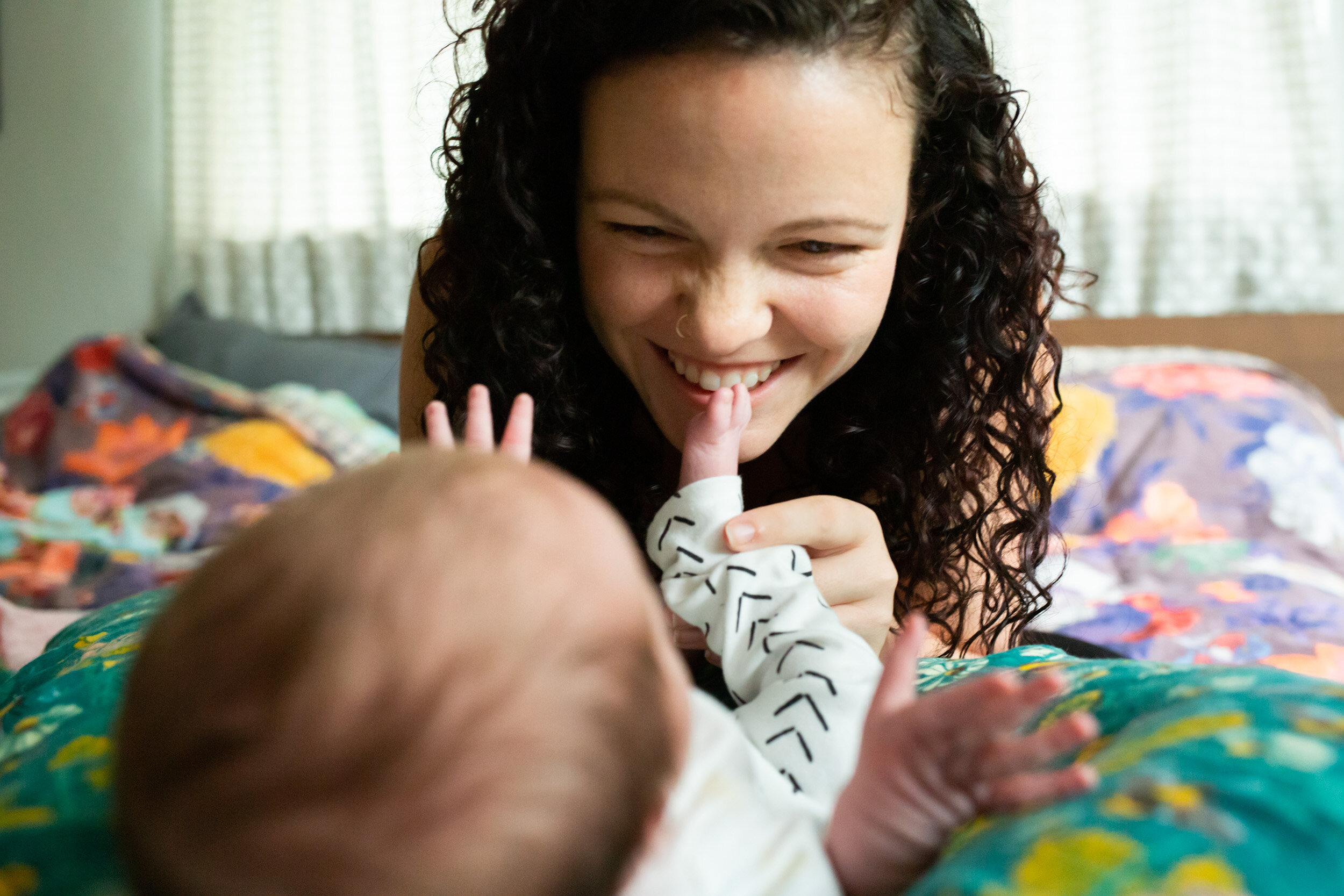 mom smiling and scrunching her nose while kissing her newborn baby's feet