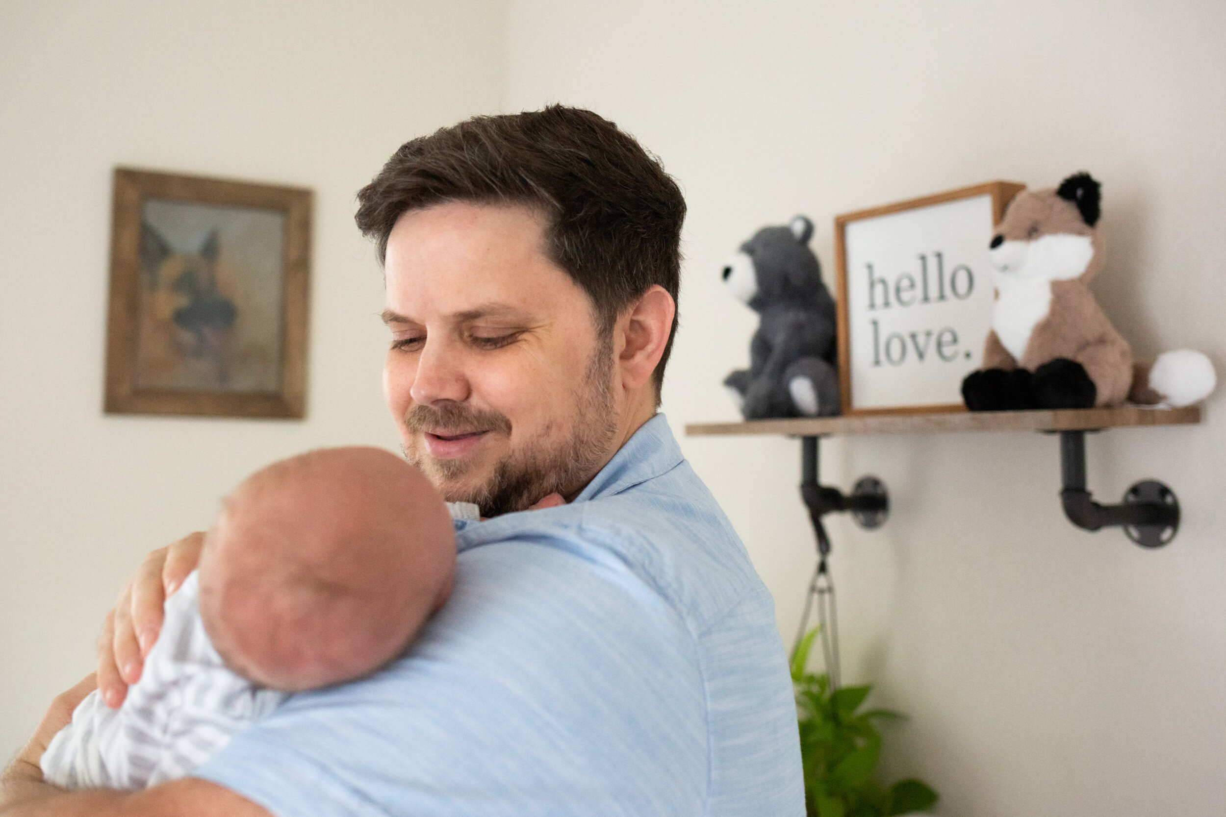 new dad holding newborn baby boy in nursery