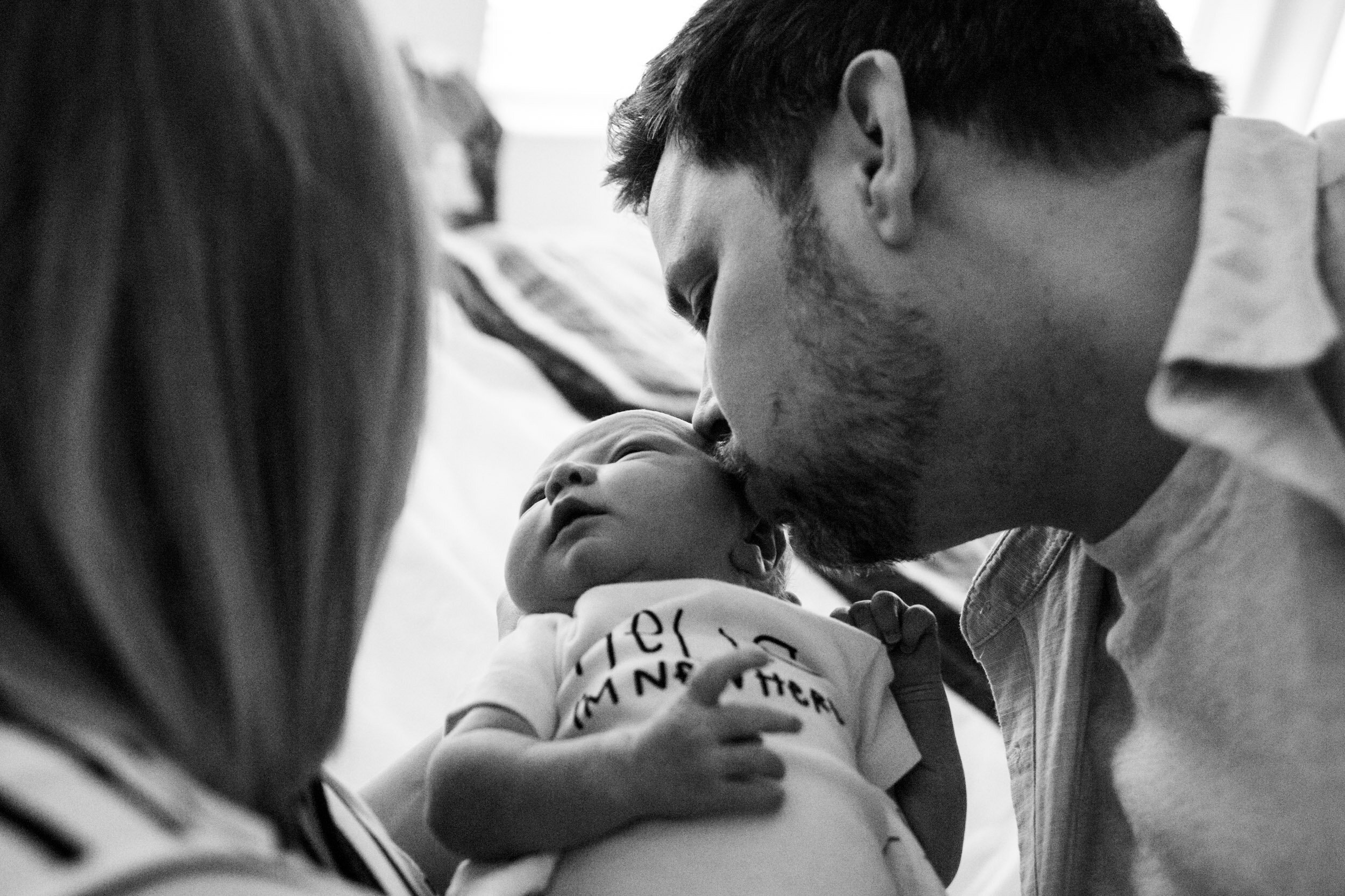 dad kissing newborn baby boy