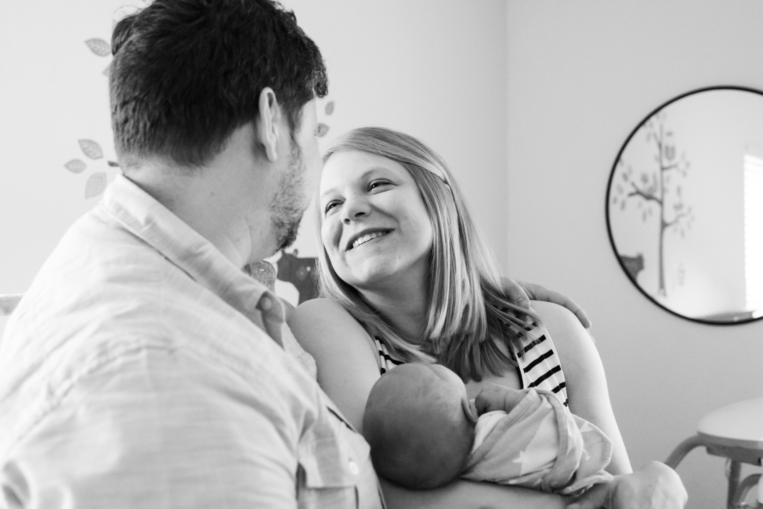 new mom looking at her husband while holding their newborn baby