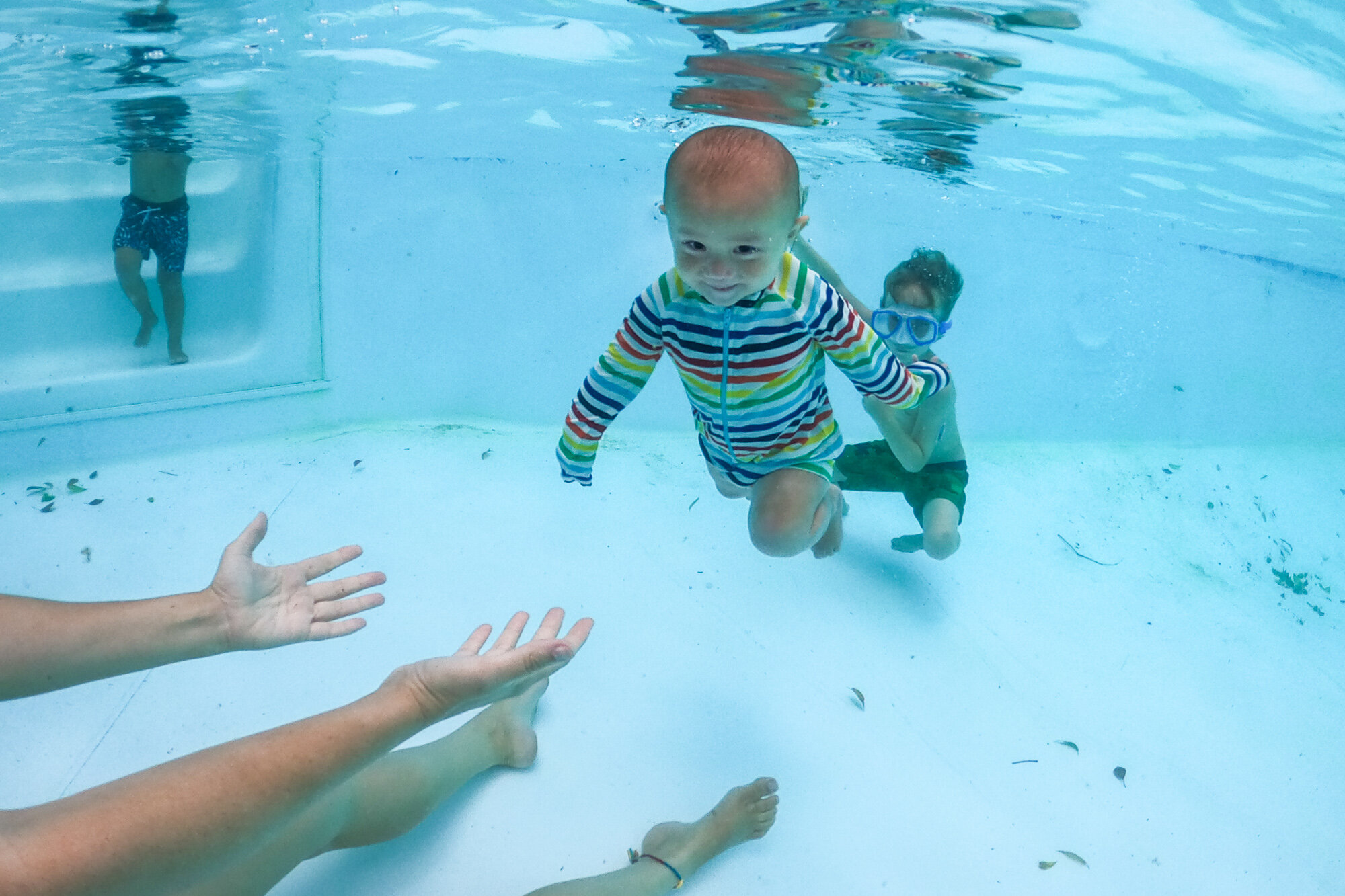 baby boy smiling while swimming underwater