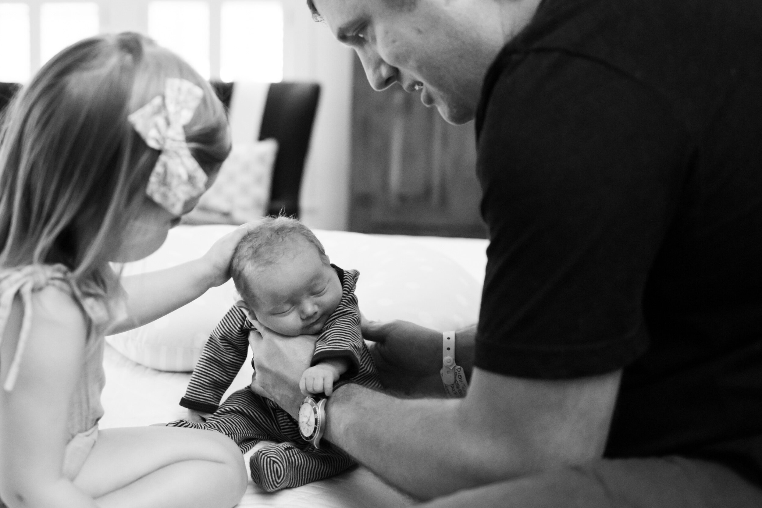 girl rubbing her newborn baby sister's head