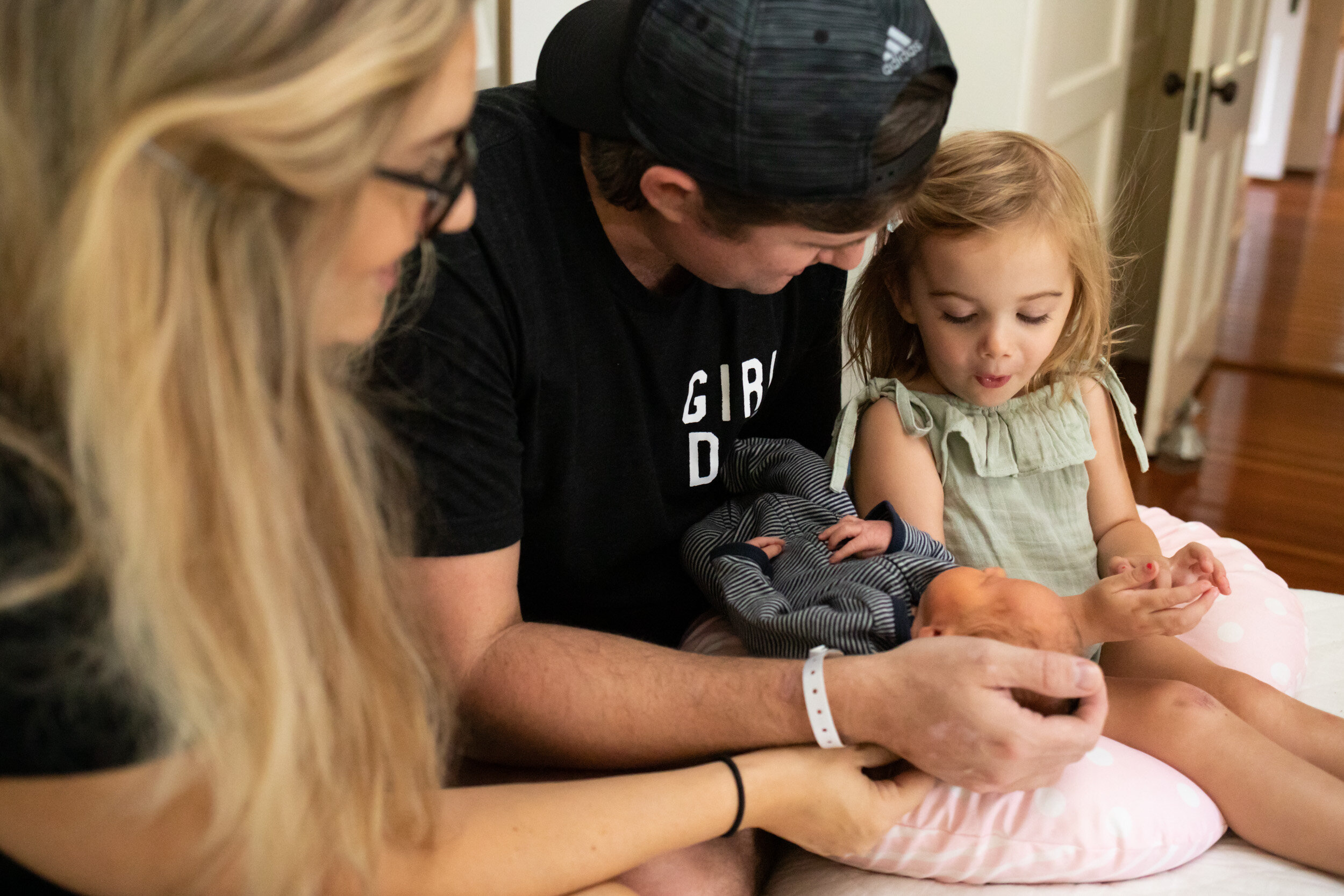 little girl with a surprised look on her face while she looks at her newborn baby sister