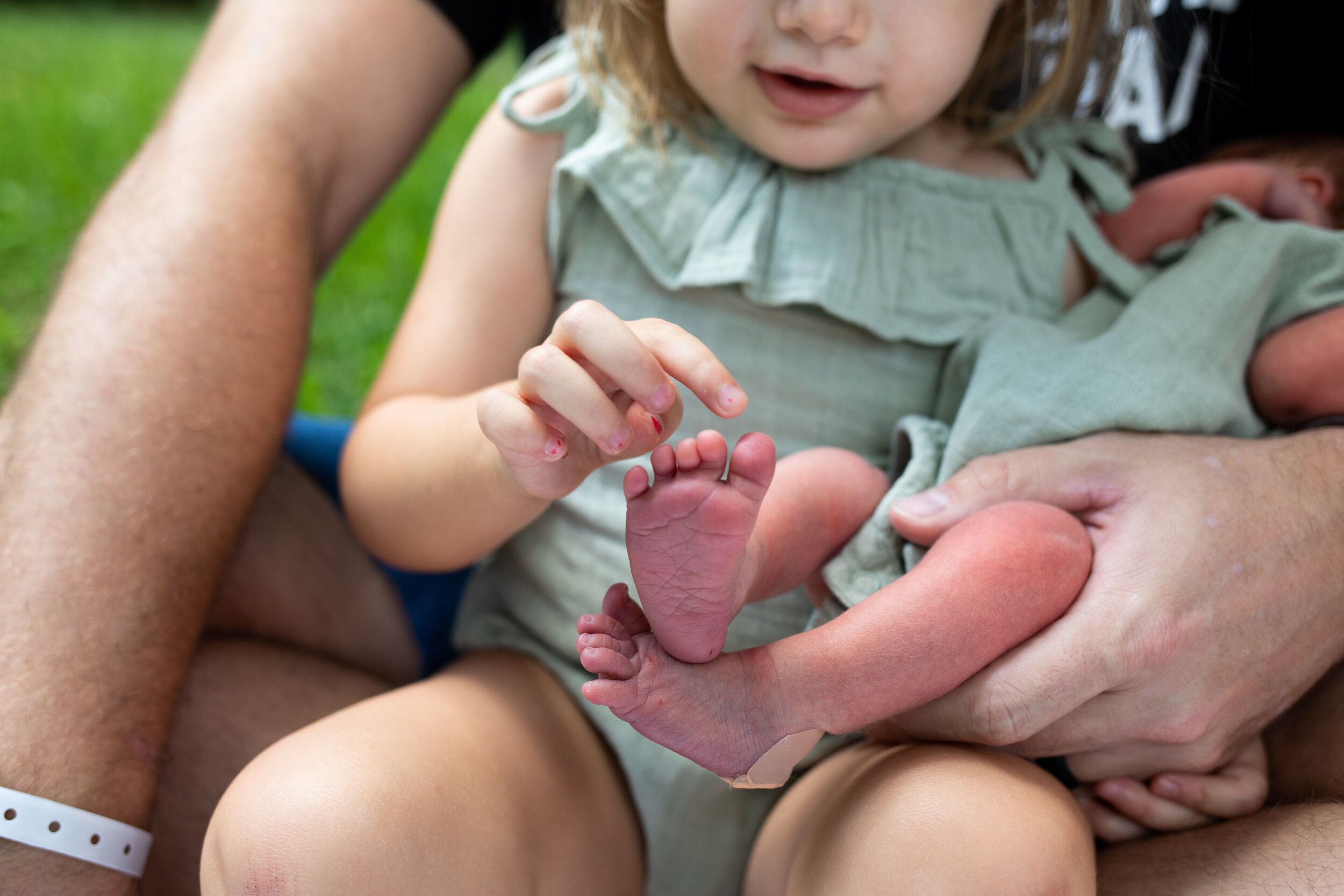 little girl counting her newborn baby sister's toes